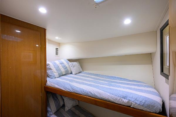 Cozy cabin interior of 2000 Viking 50 Convertible yacht with striped bedding.