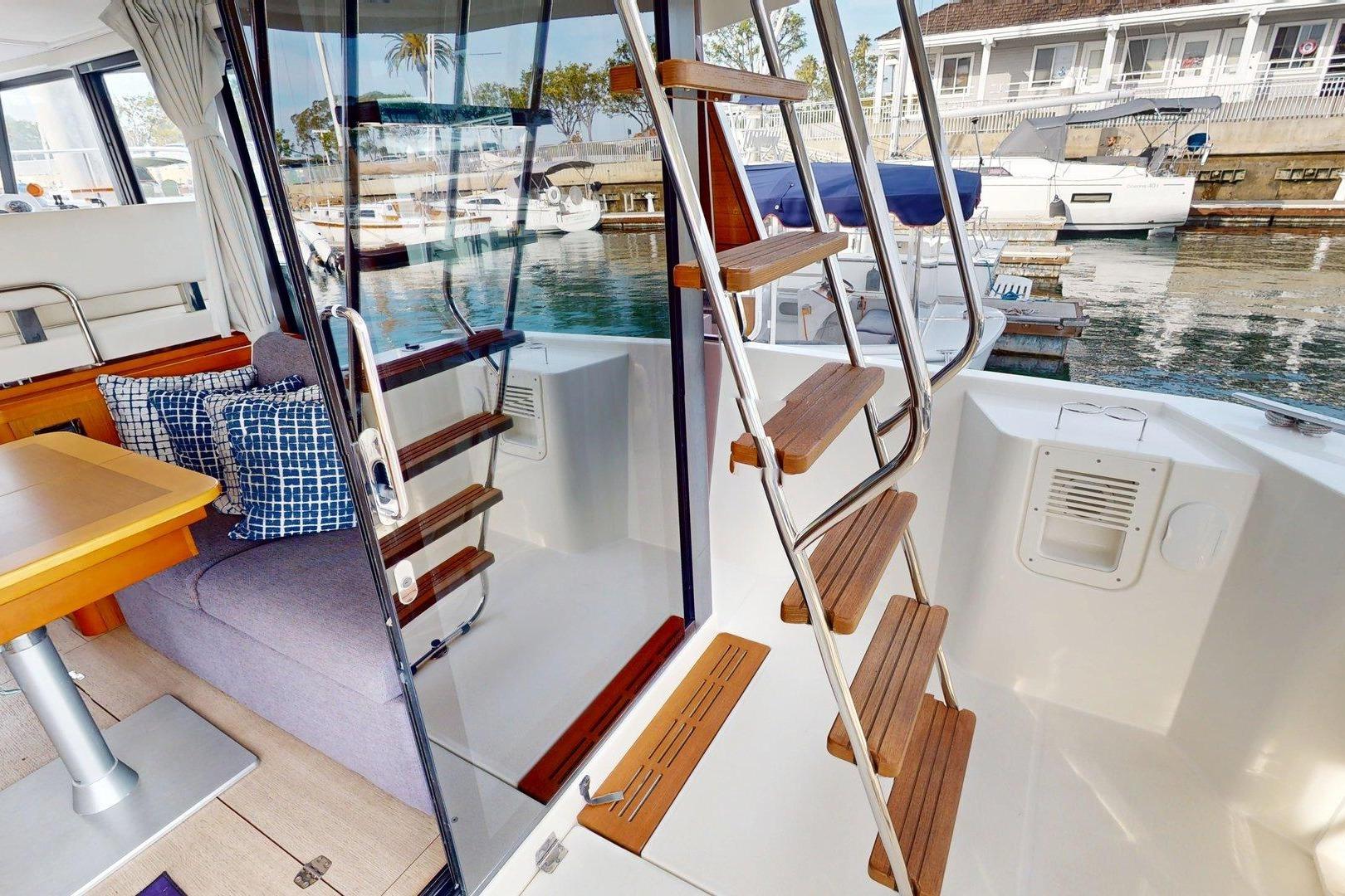 Interior view of 2021 Beneteau Swift Trawler 35, featuring wooden stairs and cozy seating area.