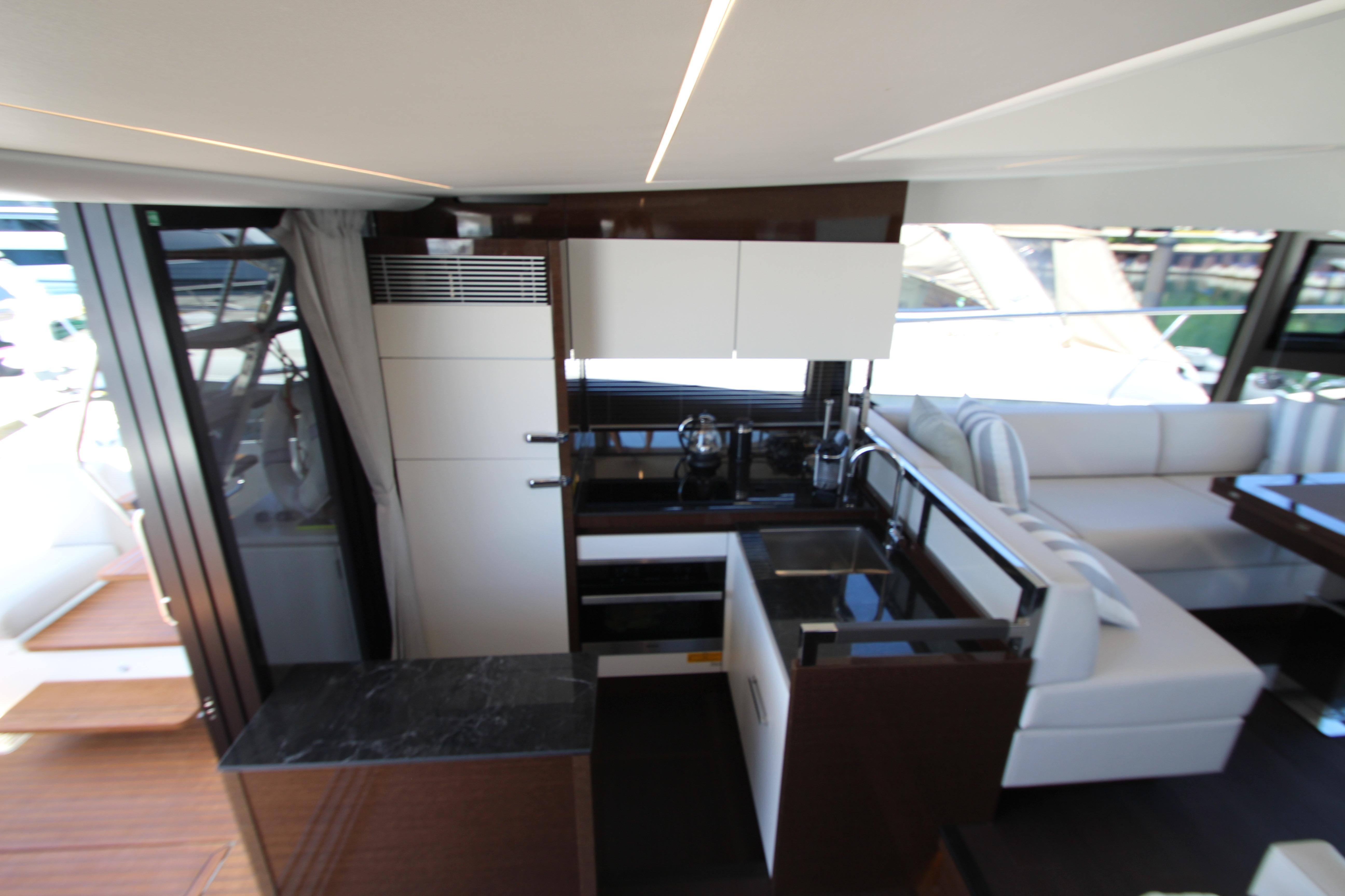 Luxurious interior of 2022 Prestige 520 yacht featuring modern kitchen and seating area.