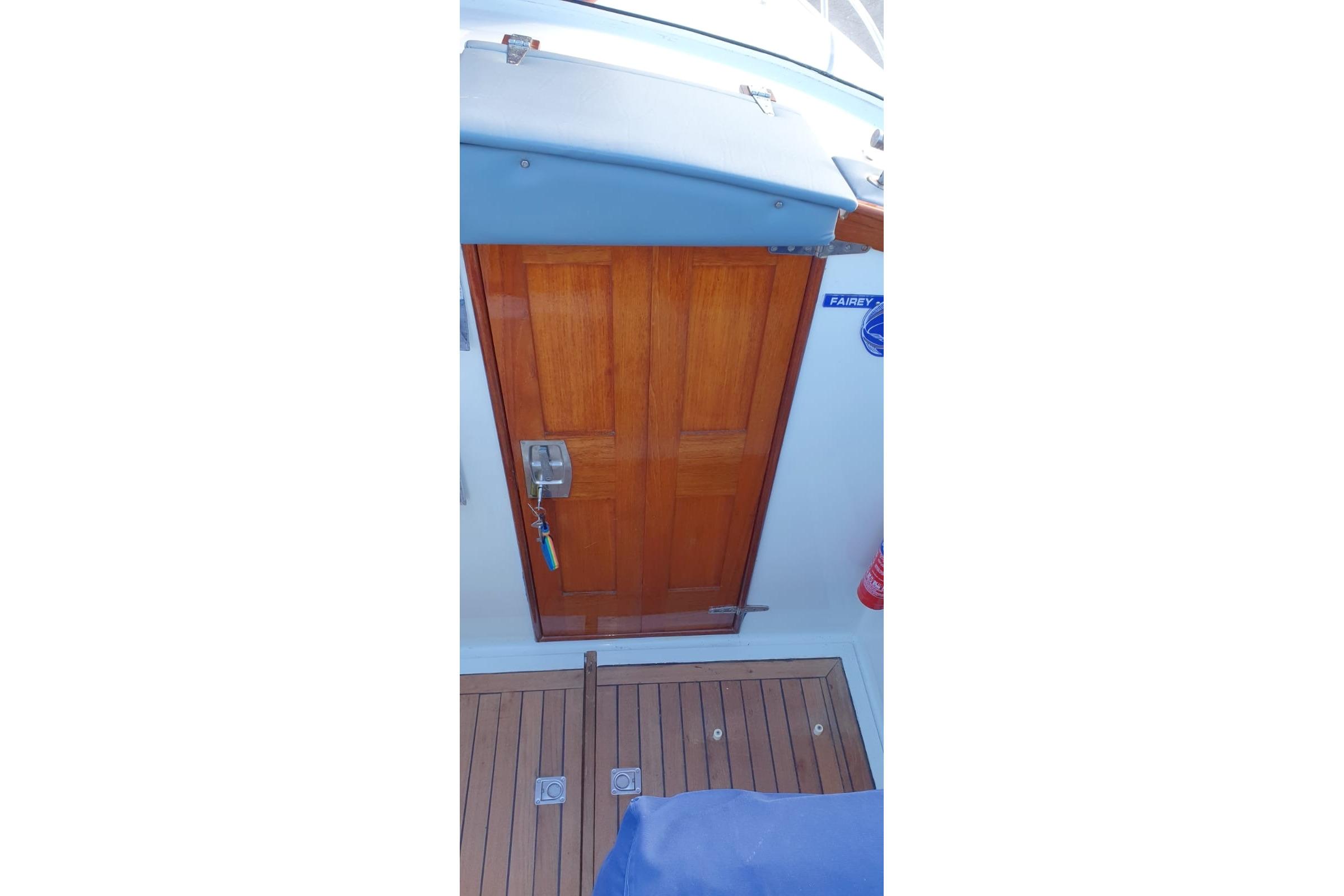 Wooden cabin door on 1989 Fairey Spearfish MKIII boat, with teak deck and blue upholstery.