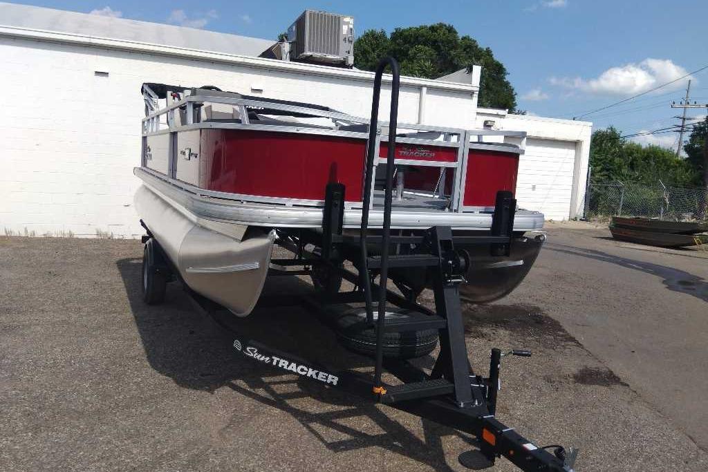 2026 Sun Tracker Bass Buggy 18 DLX pontoon boat on trailer, parked outdoors.