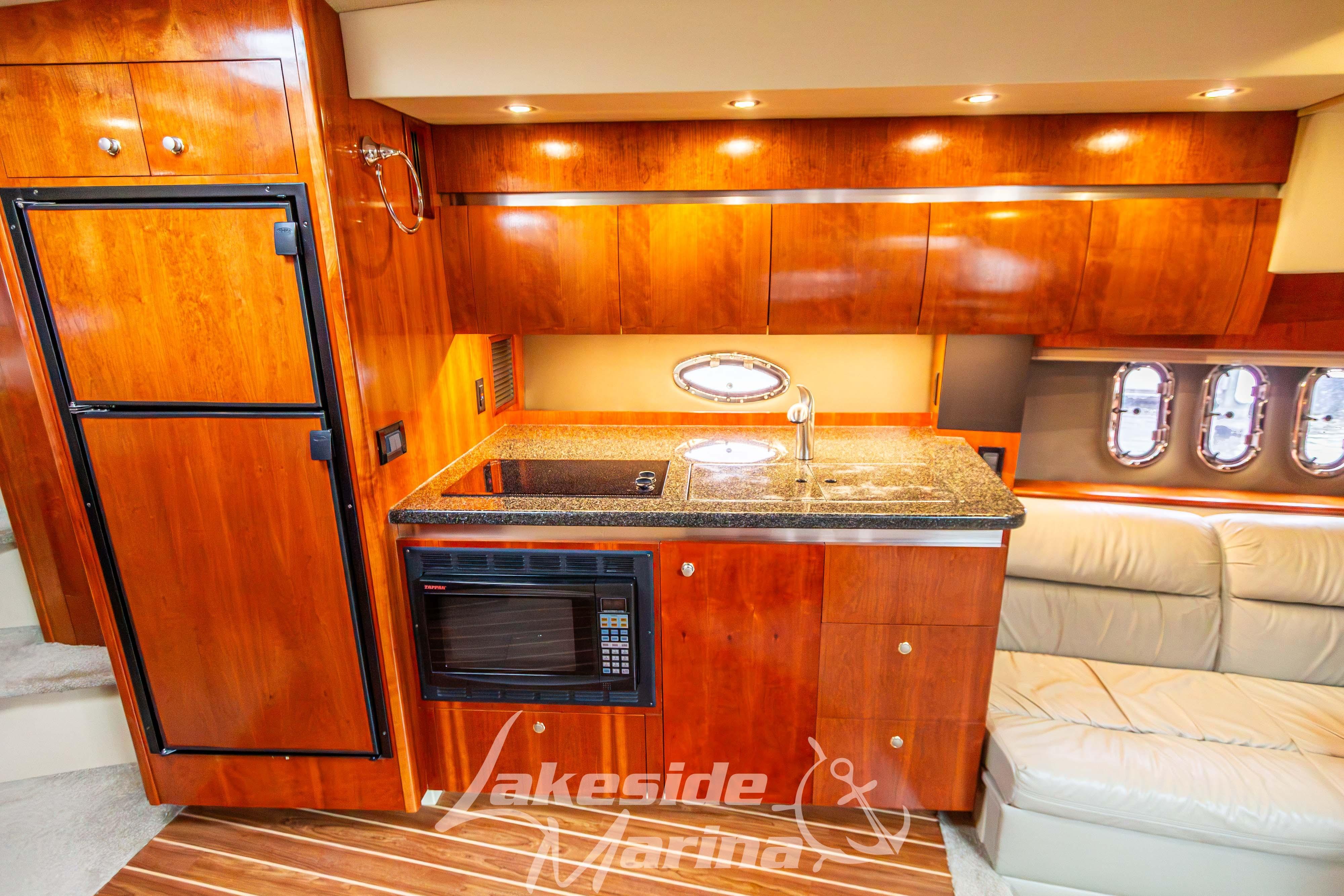 Luxurious 2006 Cruisers Yachts 420 Express interior kitchen with wood cabinetry and modern appliances.
