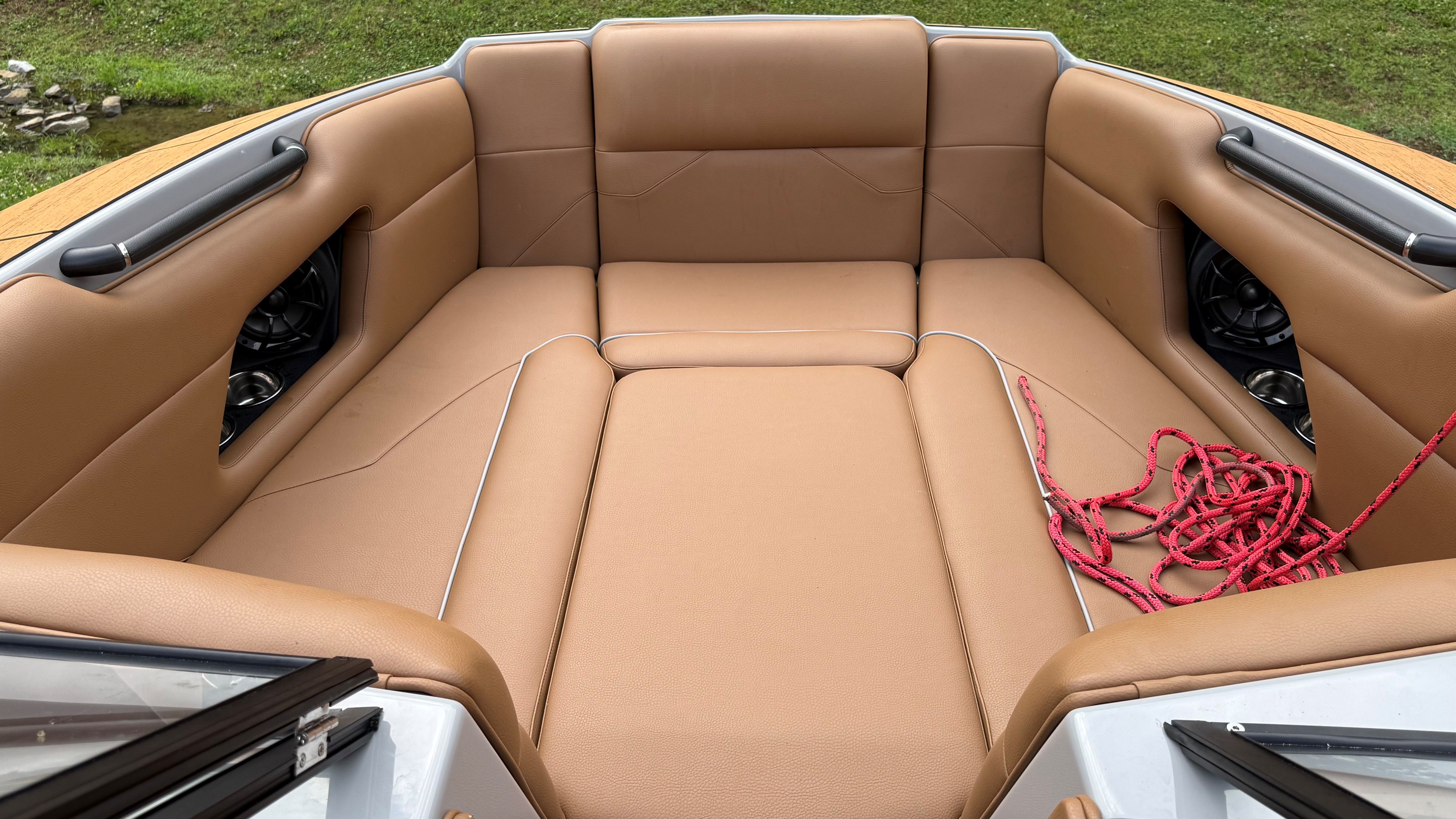 The image shows the bow area of a Malibu Mojo boat with brown upholstery and red ropes.