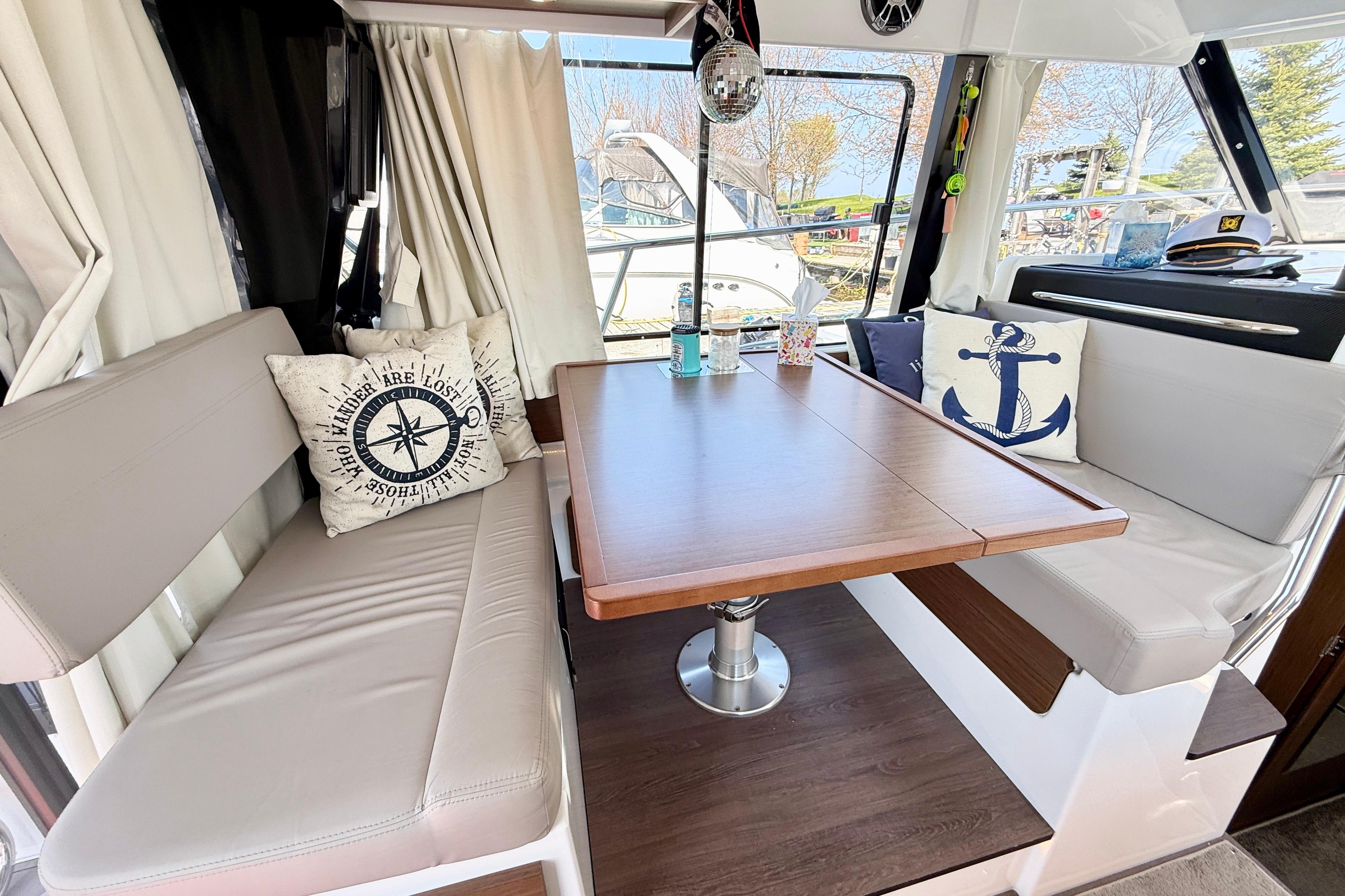Interior of 2022 Jeanneau NC 1095 Fly with nautical-themed cushions and wooden table.