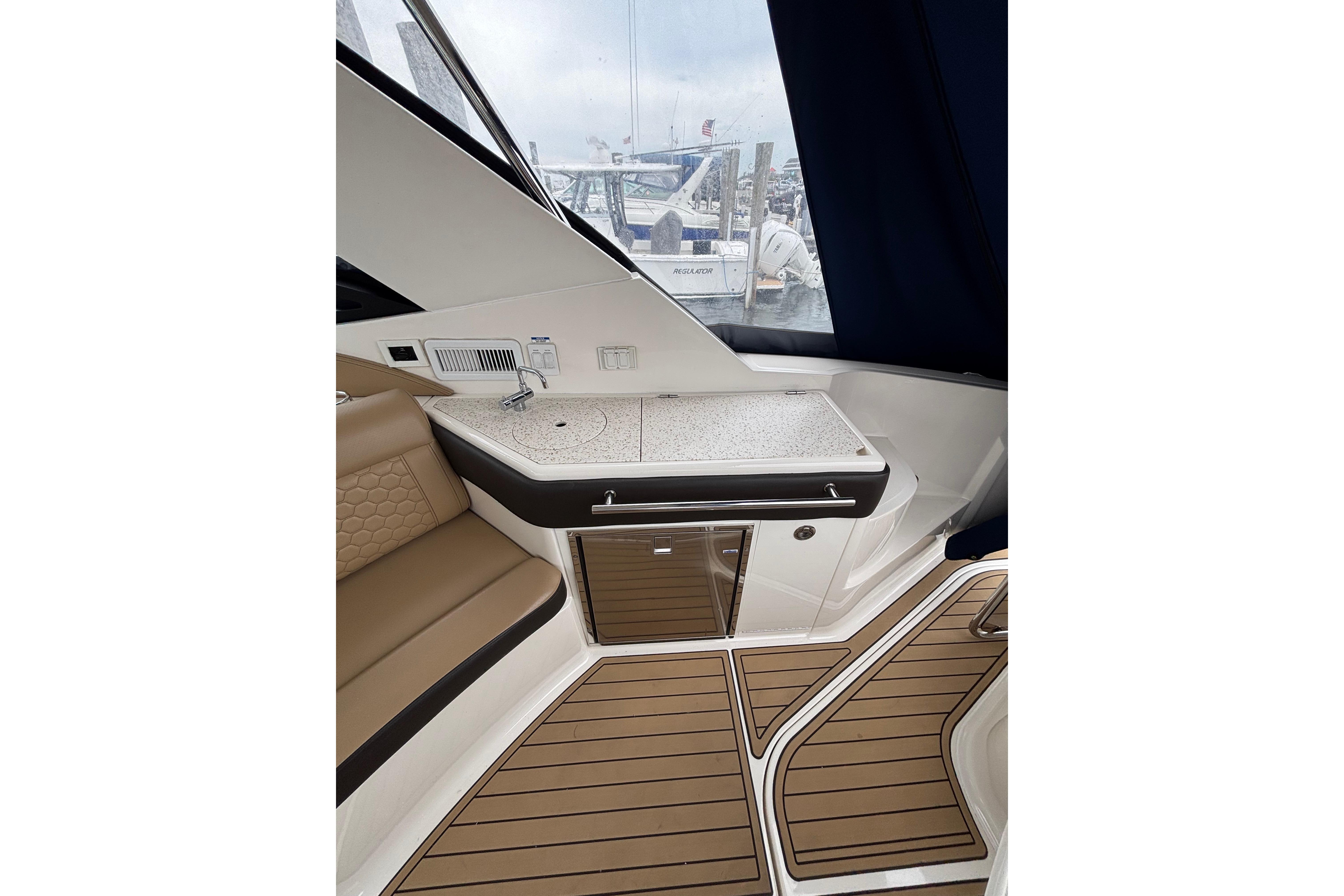 Interior of 2021 Sea Ray Sundancer 320 Outboard with seating and kitchenette area.