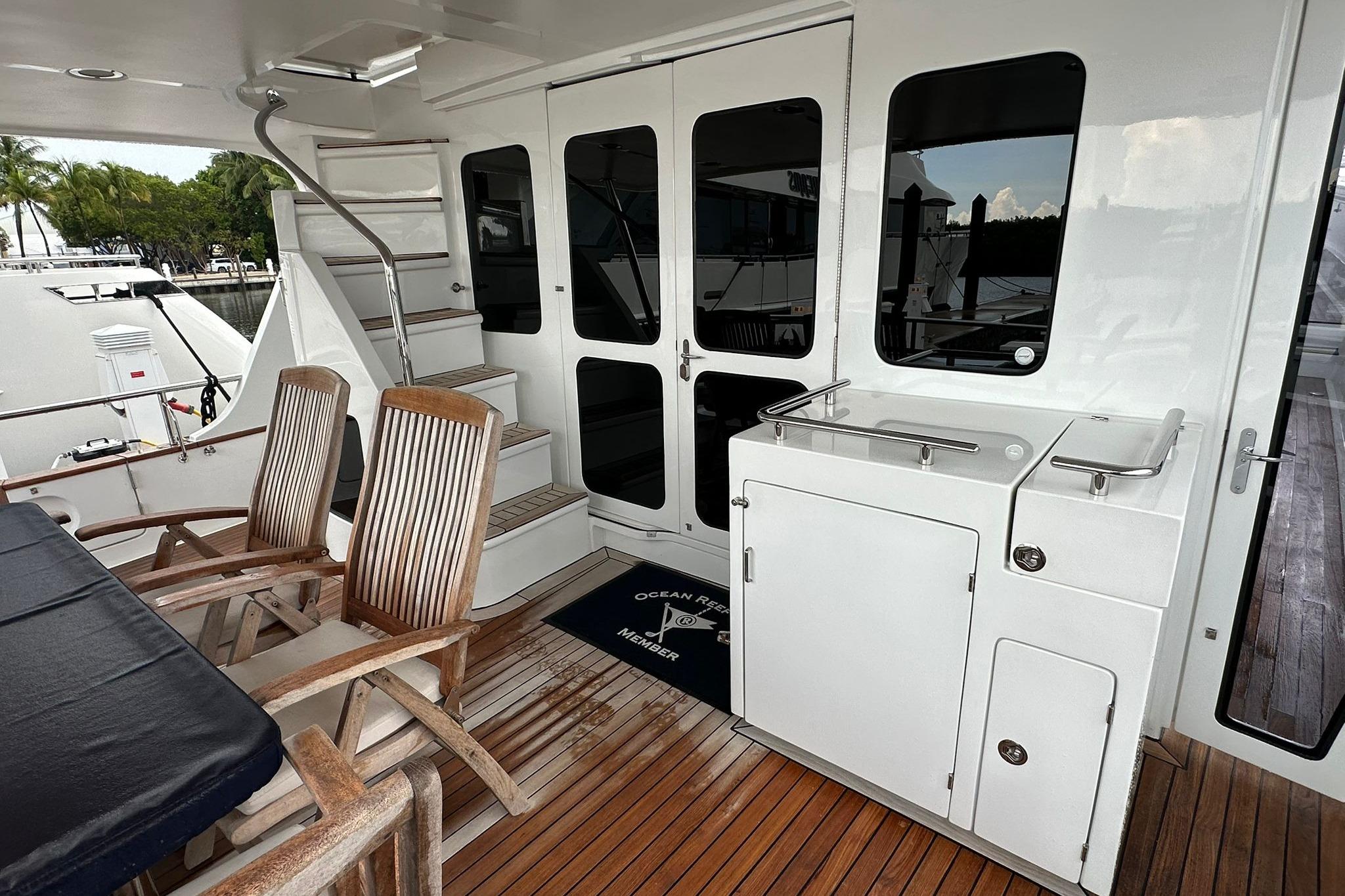 2023 Marlow Explorer 66E-CB yacht deck with wooden chairs and stairs.