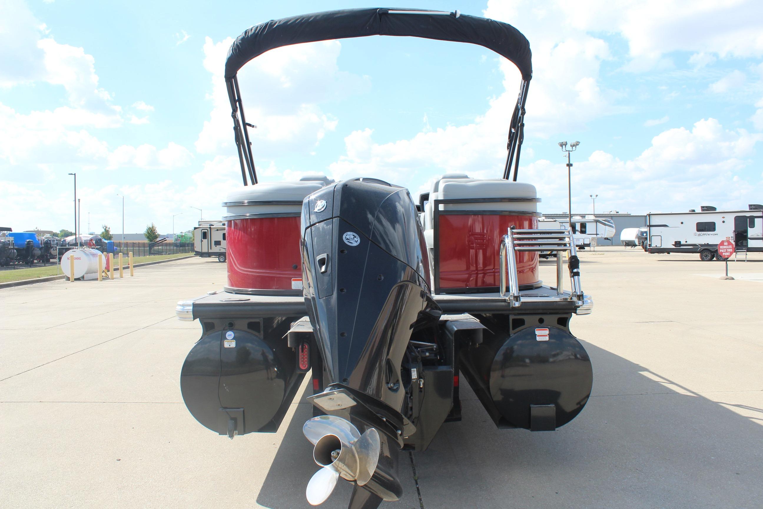 2025 Regency 230 DL3 pontoon boat with outboard motor, parked outdoors.