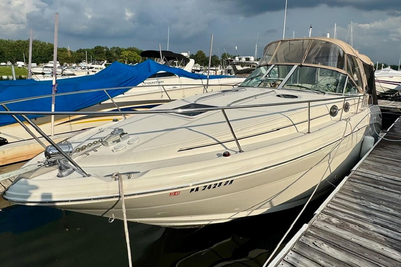 2003 Sea Ray 300 Sundancer docked at marina under cloudy sky.