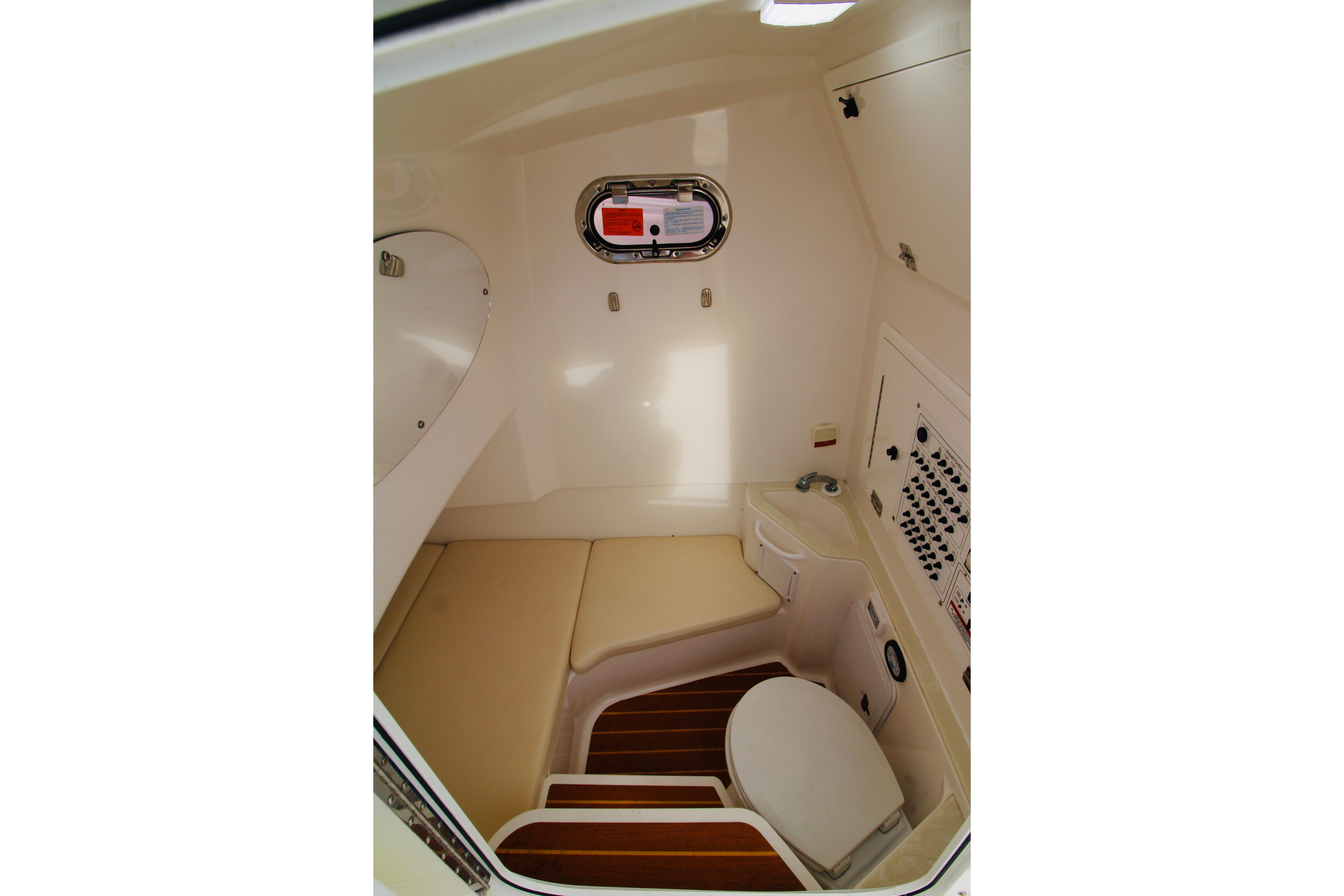 Interior of 2022 Edgewater 280CC boat featuring compact bathroom with toilet and seating.