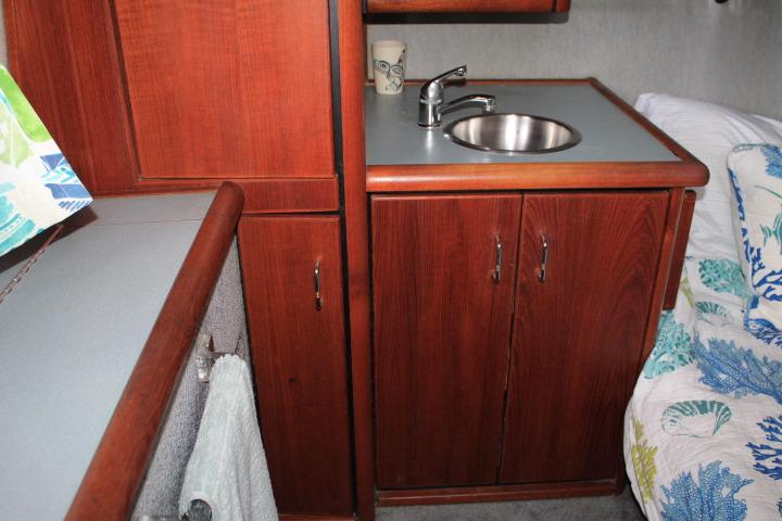 Interior of 1992 Bayliner 3288 Motoryacht with wooden cabinetry and compact sink area.