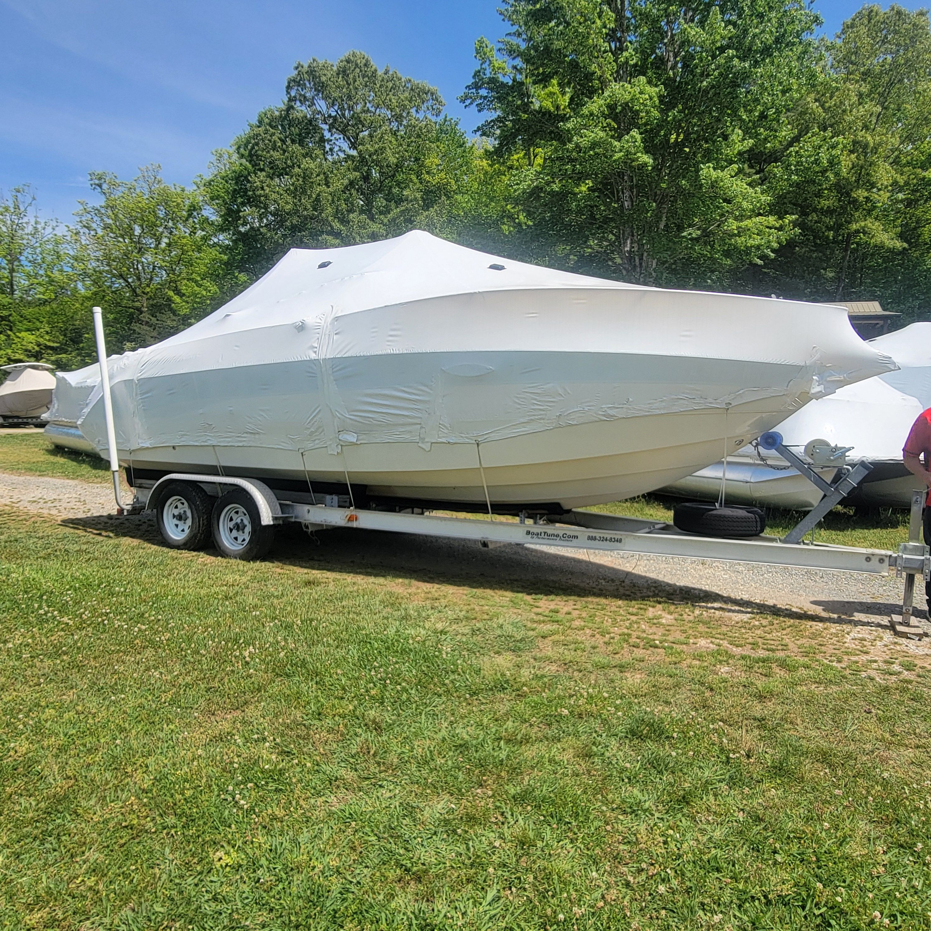 A 2002 Stingray 240 CR boat on a trailer with a cover, parked on grass.