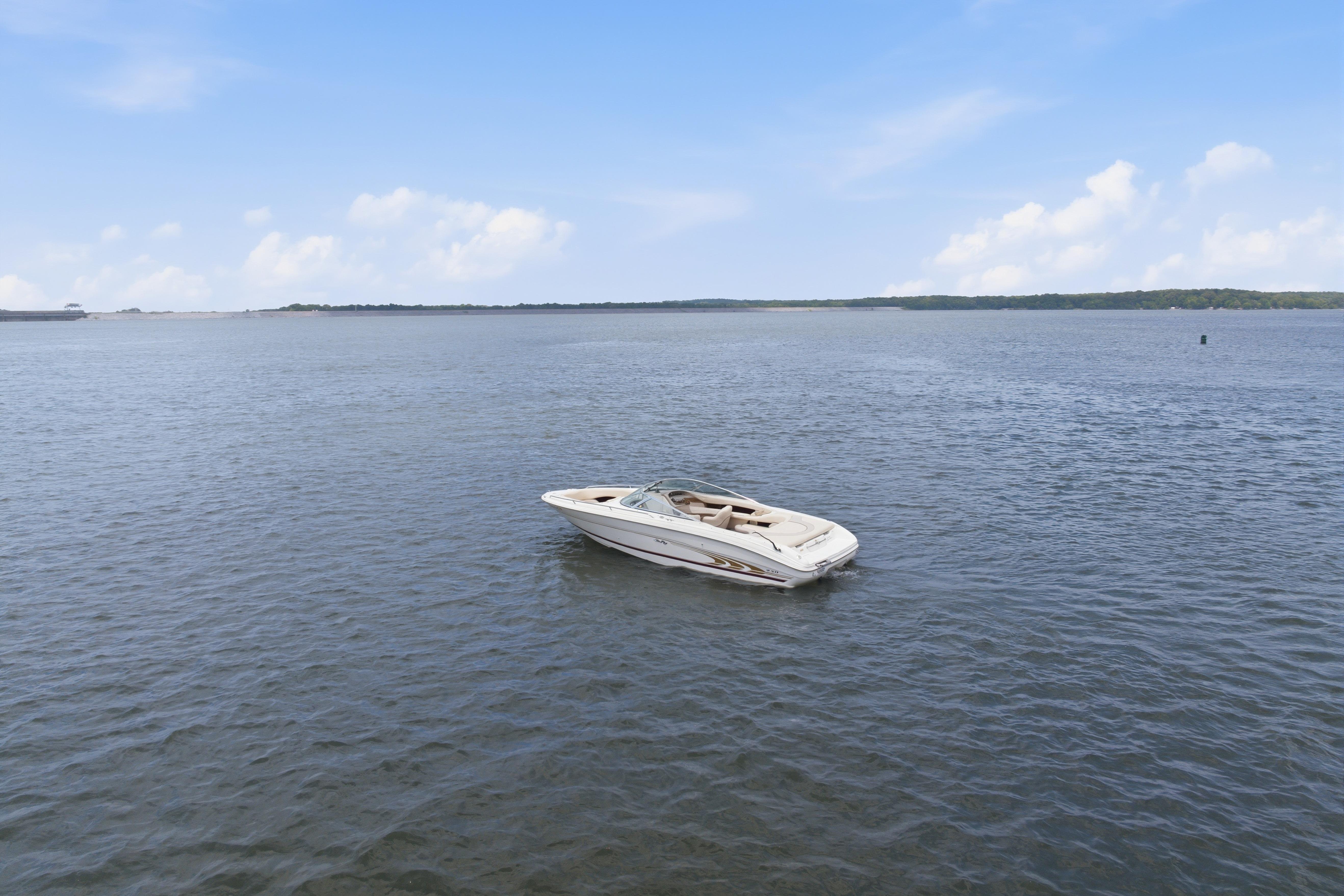 1997 Sea Ray 230 Signature boat floating on calm water under a clear blue sky.