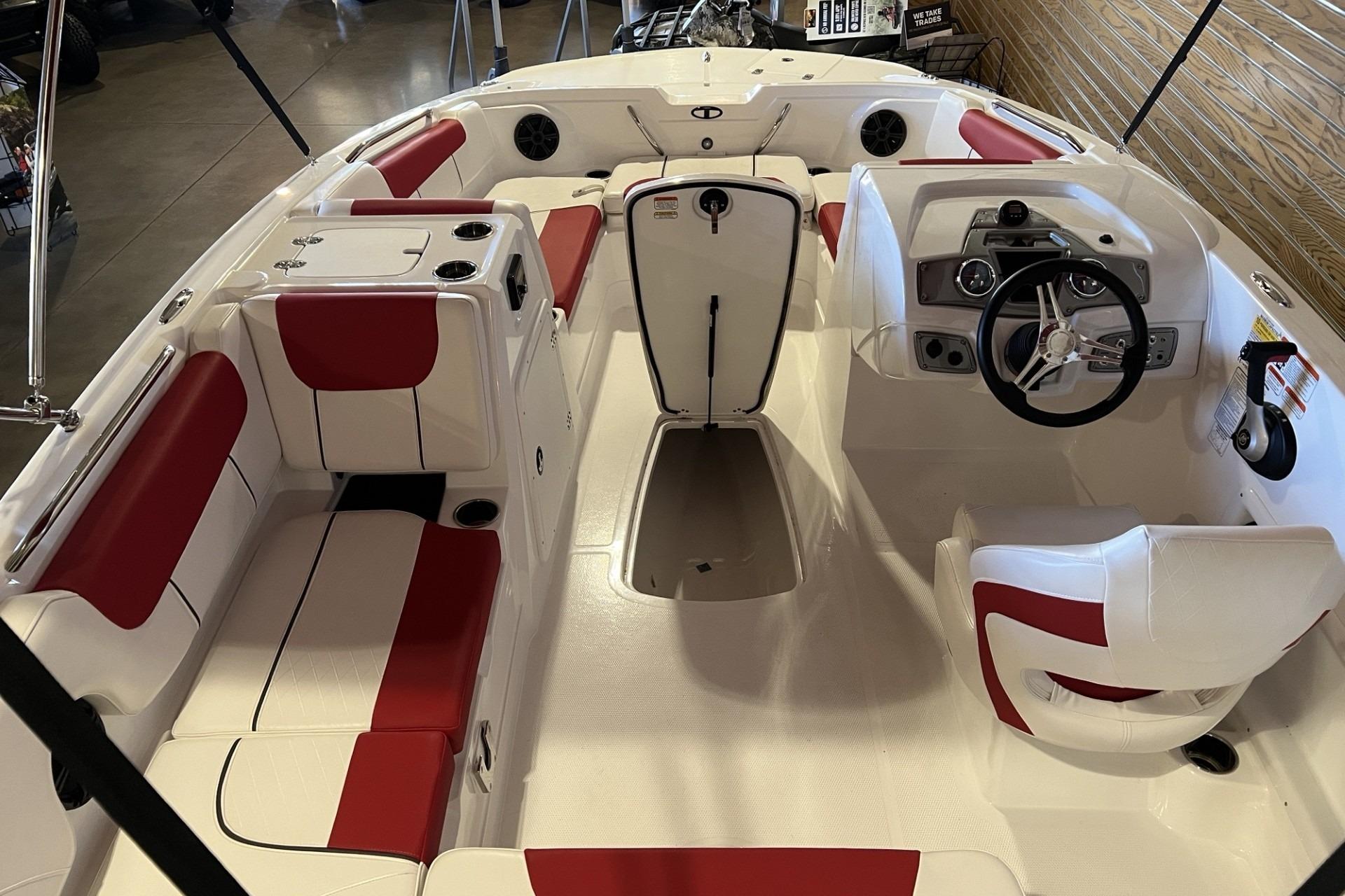 Interior of 2025 Tahoe 1950 boat with red and white seating, steering wheel, and controls.