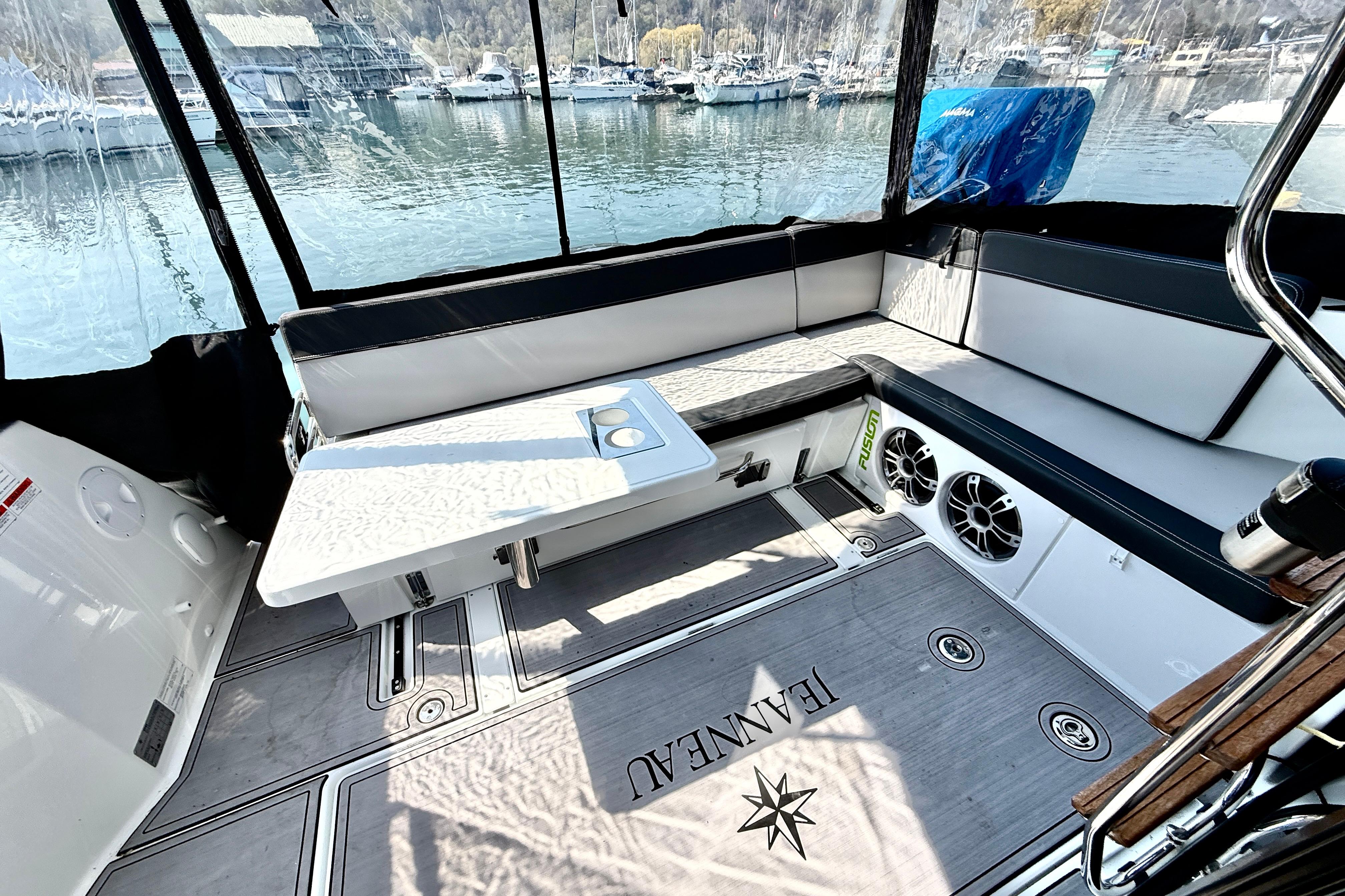 Interior of 2022 Jeanneau NC 1095 Fly boat with seating and table, docked by water.