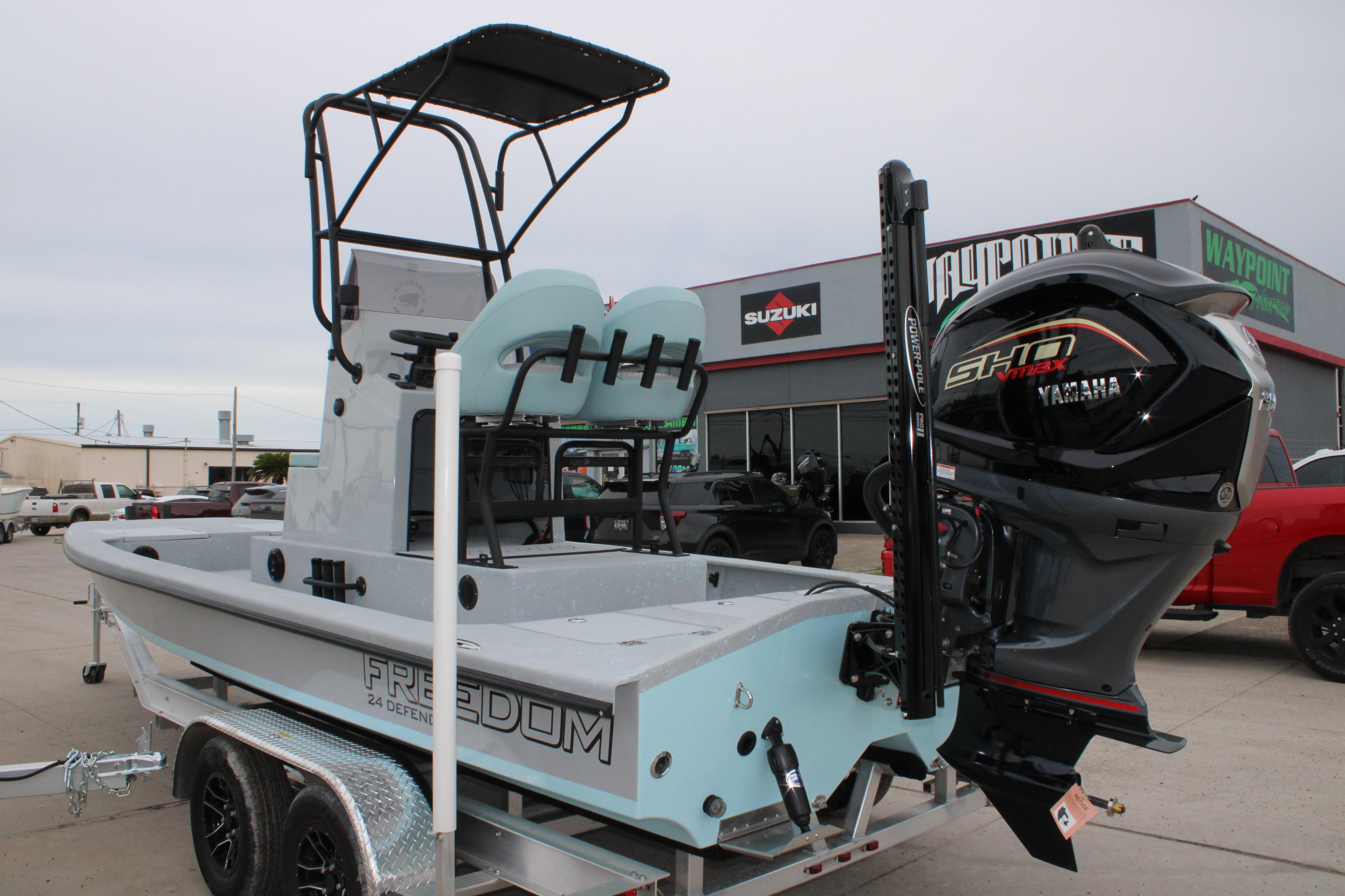2026 Freedom Boats 24 Defender with Yamaha engine on trailer, parked outside dealership.