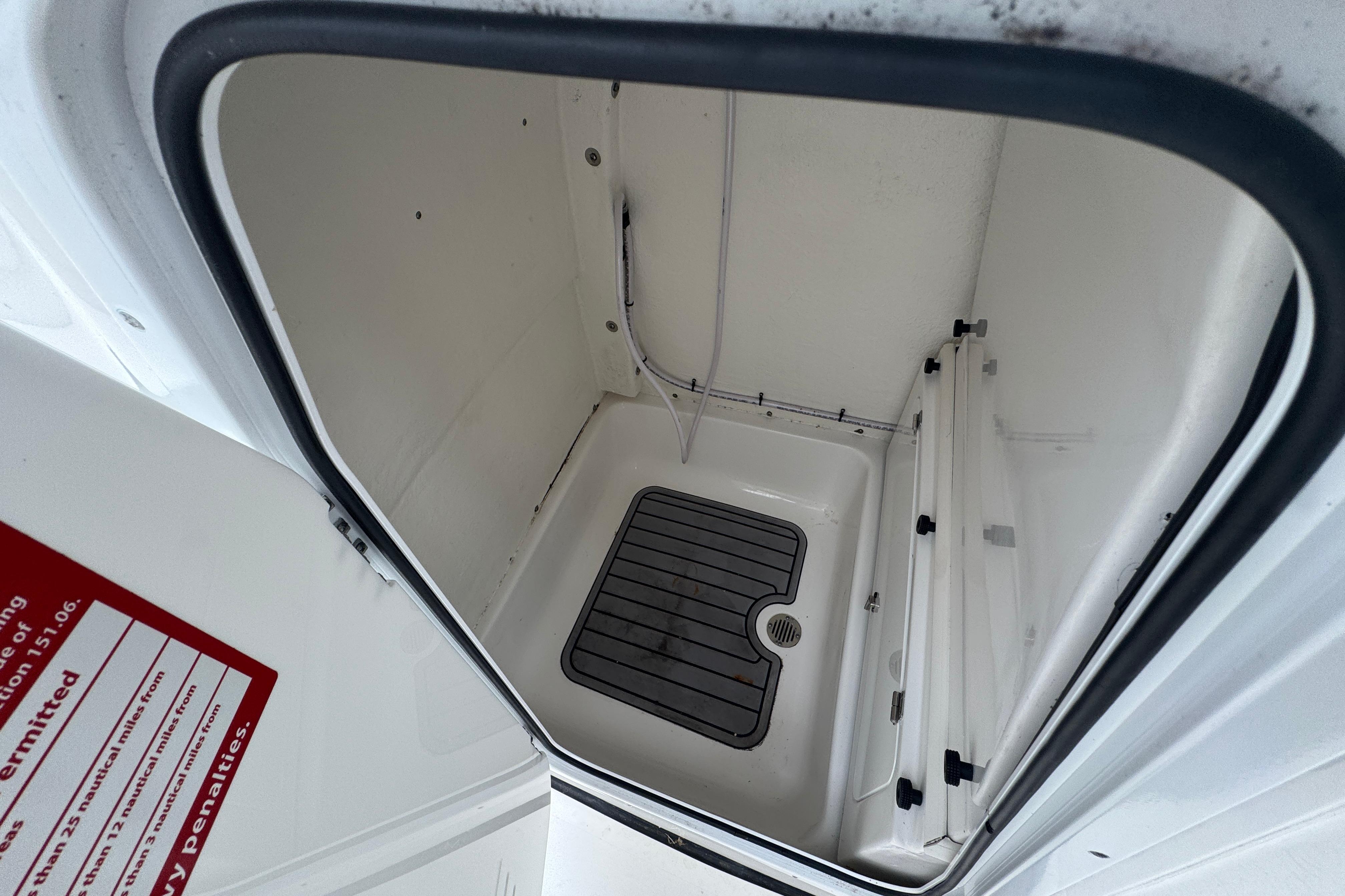 Interior storage compartment of 2022 Tidewater 232 SS boat, featuring a drain and non-slip mat.