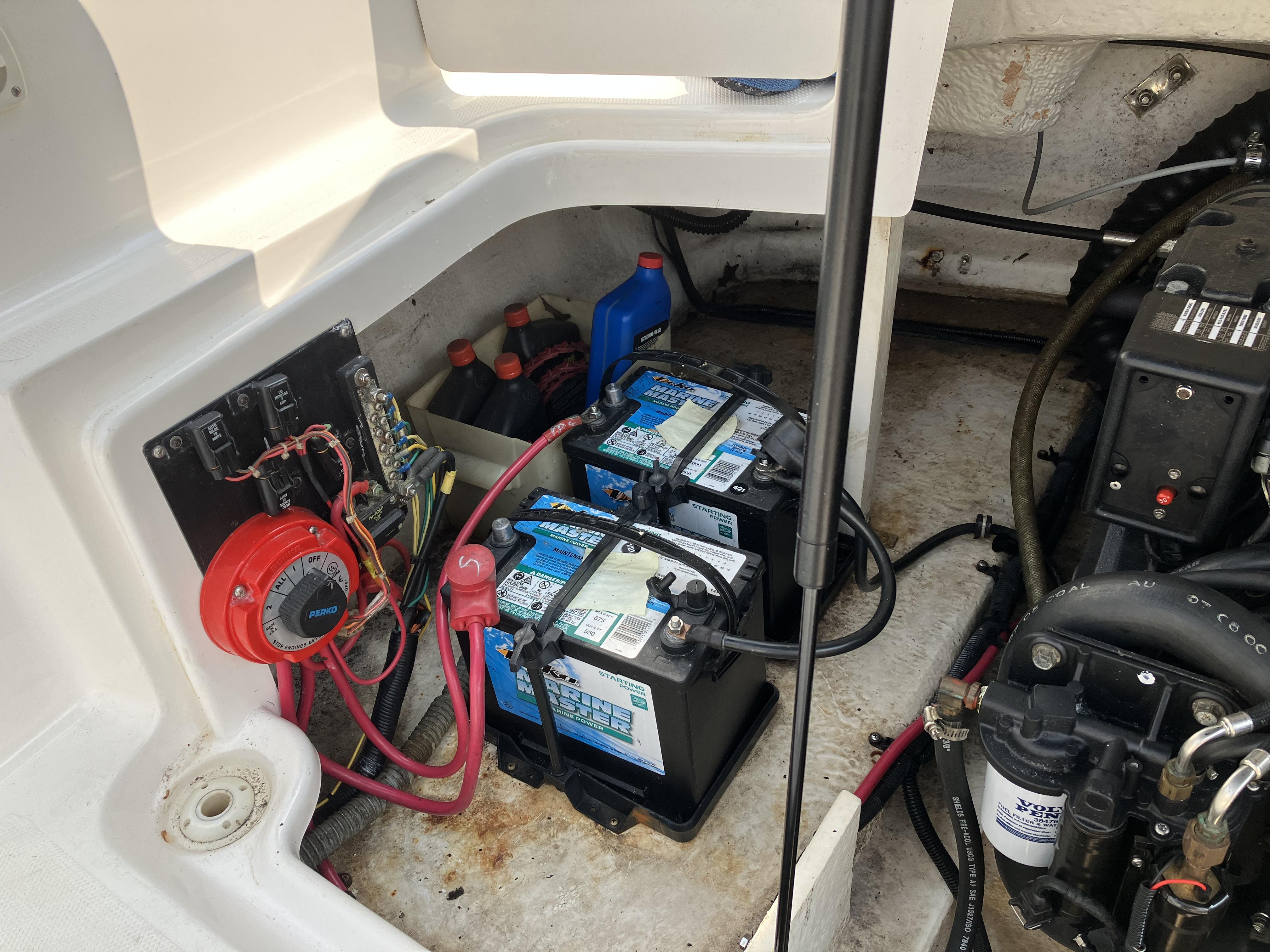View of a boat's engine compartment with batteries, cables, and an engine.
