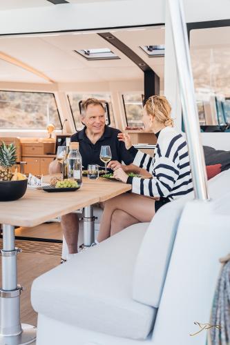 Couple dining on Nautitech 44 Open yacht, 2025 model, enjoying a meal indoors.