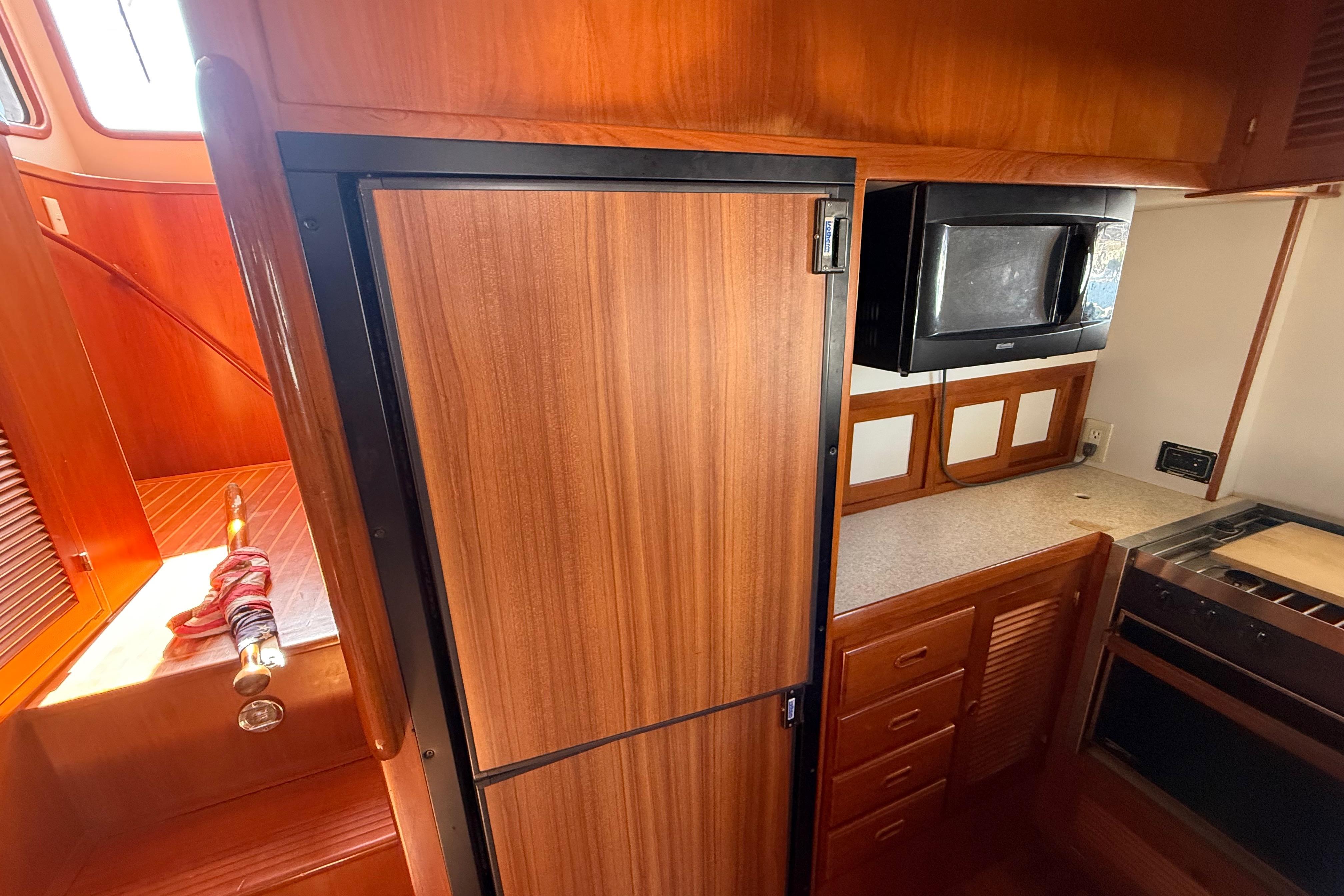 2001 Kadey-Krogen 39 yacht kitchen with wood cabinetry, fridge, microwave, and stove.