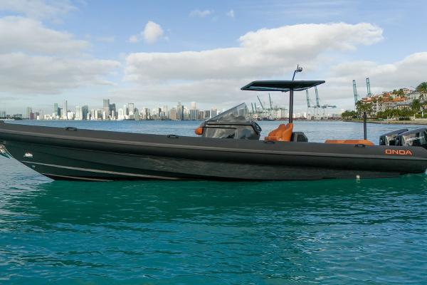 2024 Onda Magna boat on turquoise water with city skyline in the background.