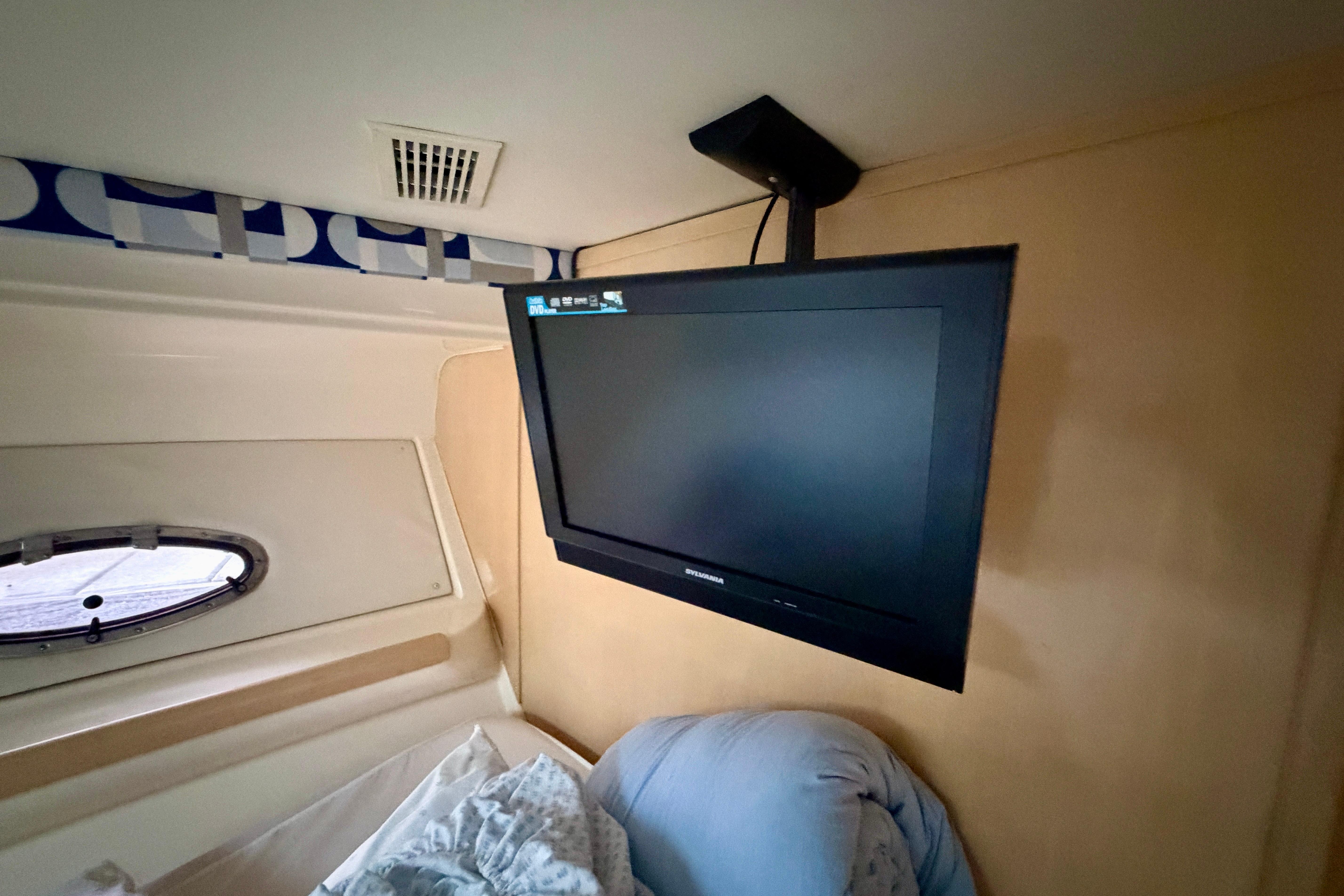 Flat-screen TV in 2000 Carver 350 Mariner cabin, near a small window and bedding.