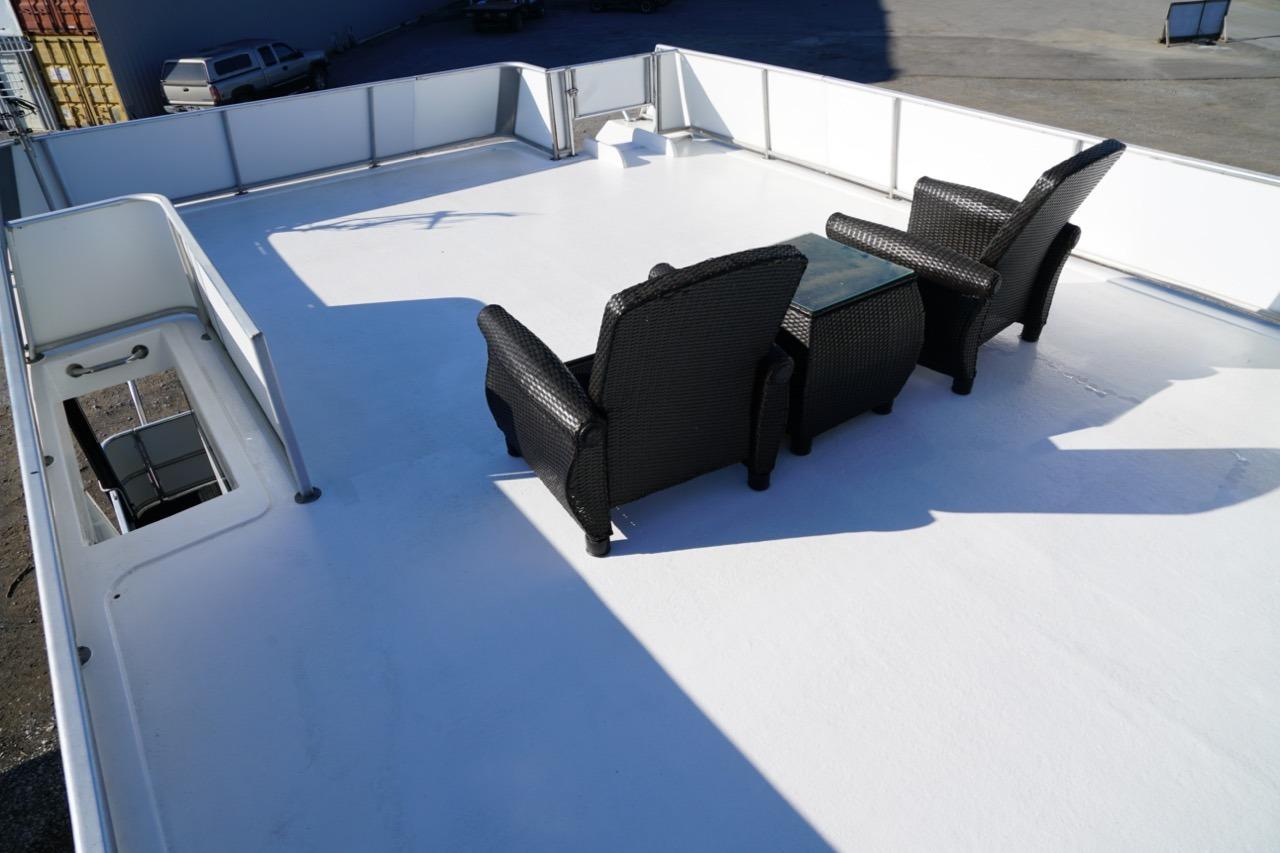 Rooftop deck of 2000 Stardust Cruisers houseboat with wicker chairs and table.