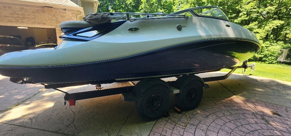 A 2007 Sea-Doo Sport Boat 230 Challenger SE on a trailer in a driveway.