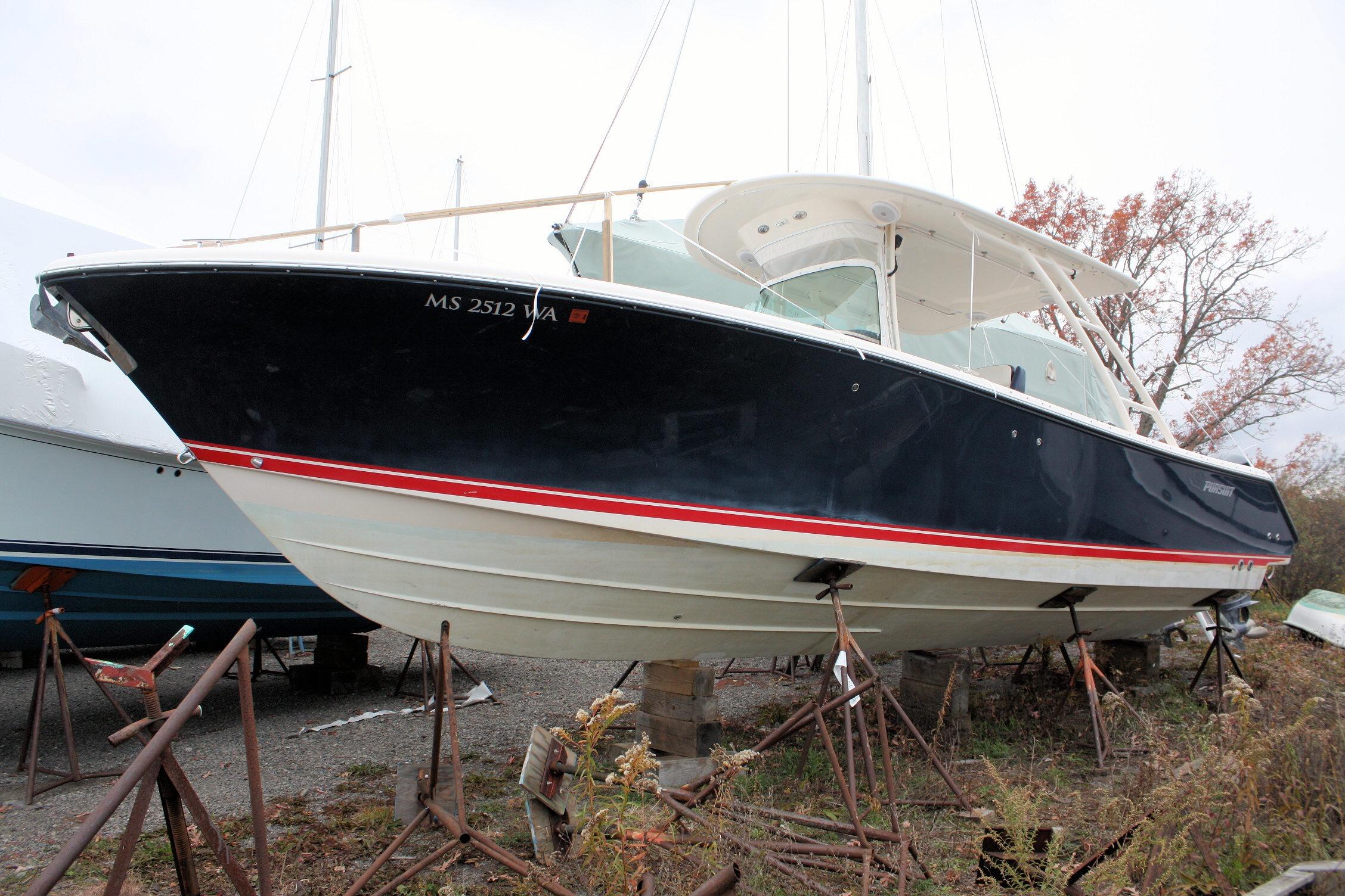 2013 Pursuit ST 310 Sport boat on stands, black hull, red stripe, outdoor storage.