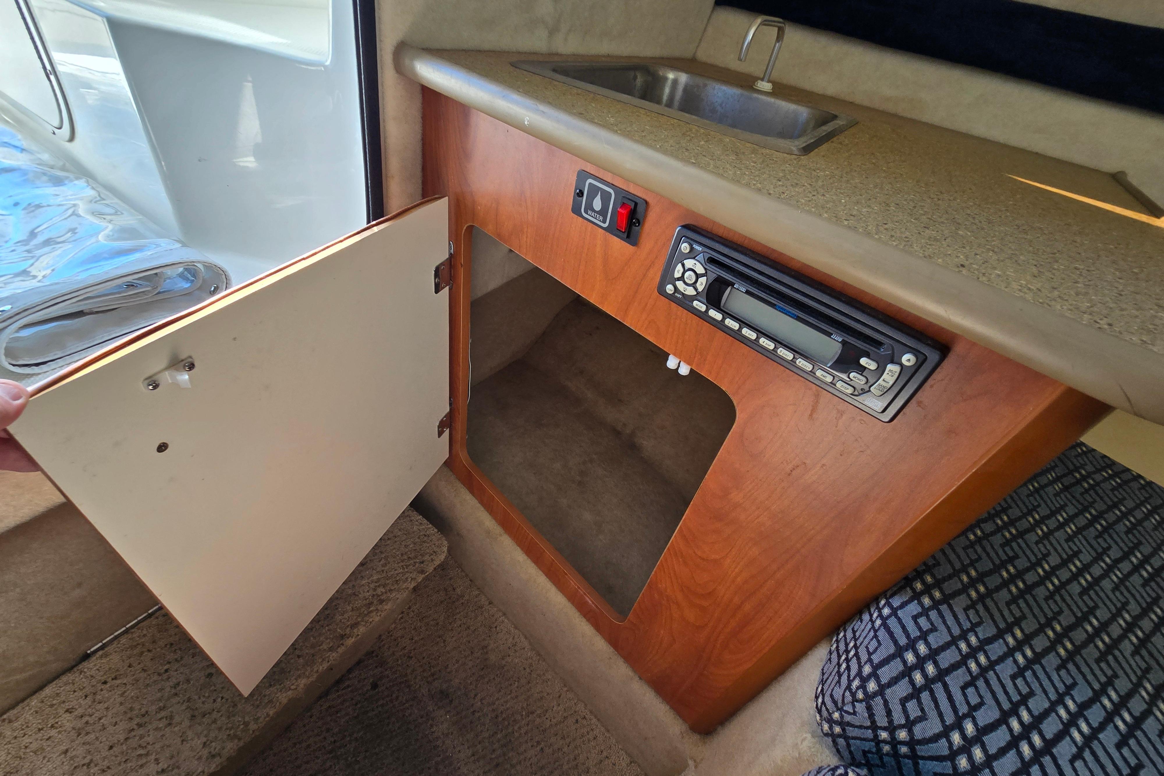 Interior of a 2006 Bayliner 222 Classic boat with a sink and storage cabinet.