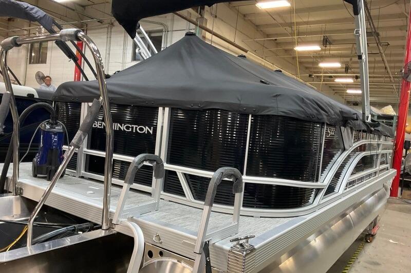 2026 Bennington 22 SSRSF pontoon boat with black cover in a warehouse setting.