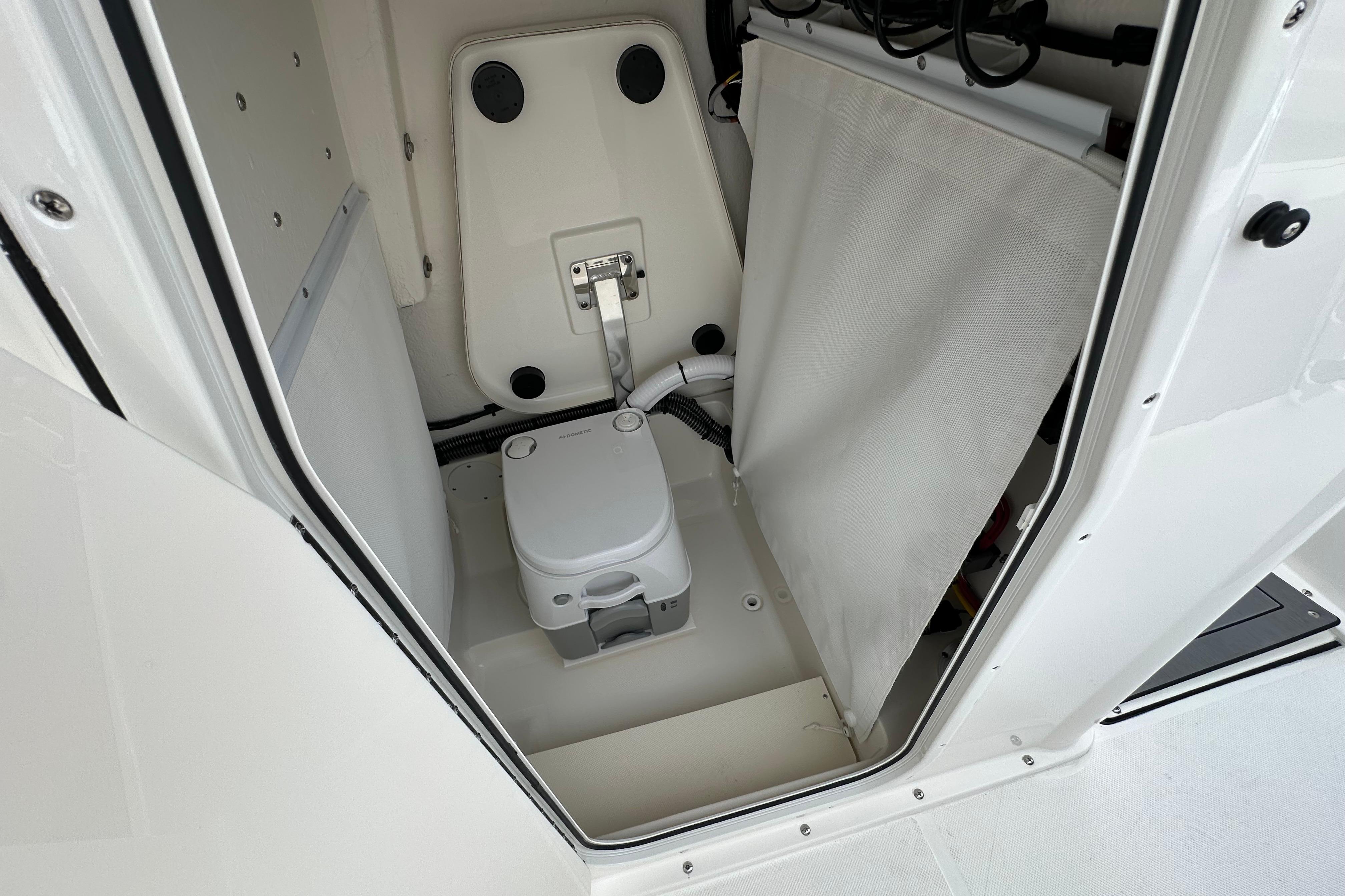 Interior of 2027 Sea Born LX24 Center Console boat with compact marine toilet.