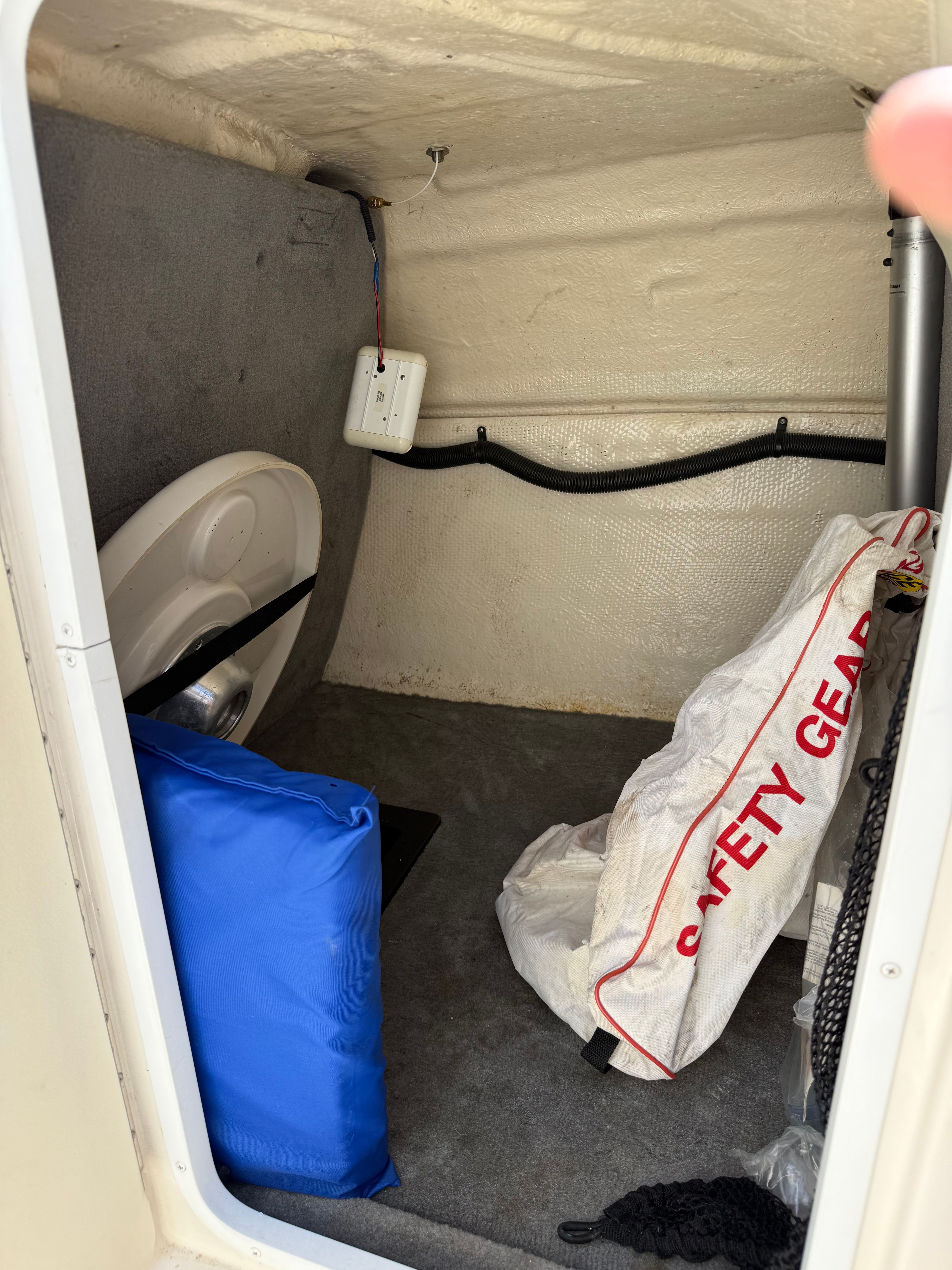 A storage area in the boat with safety gear and a blue bag.