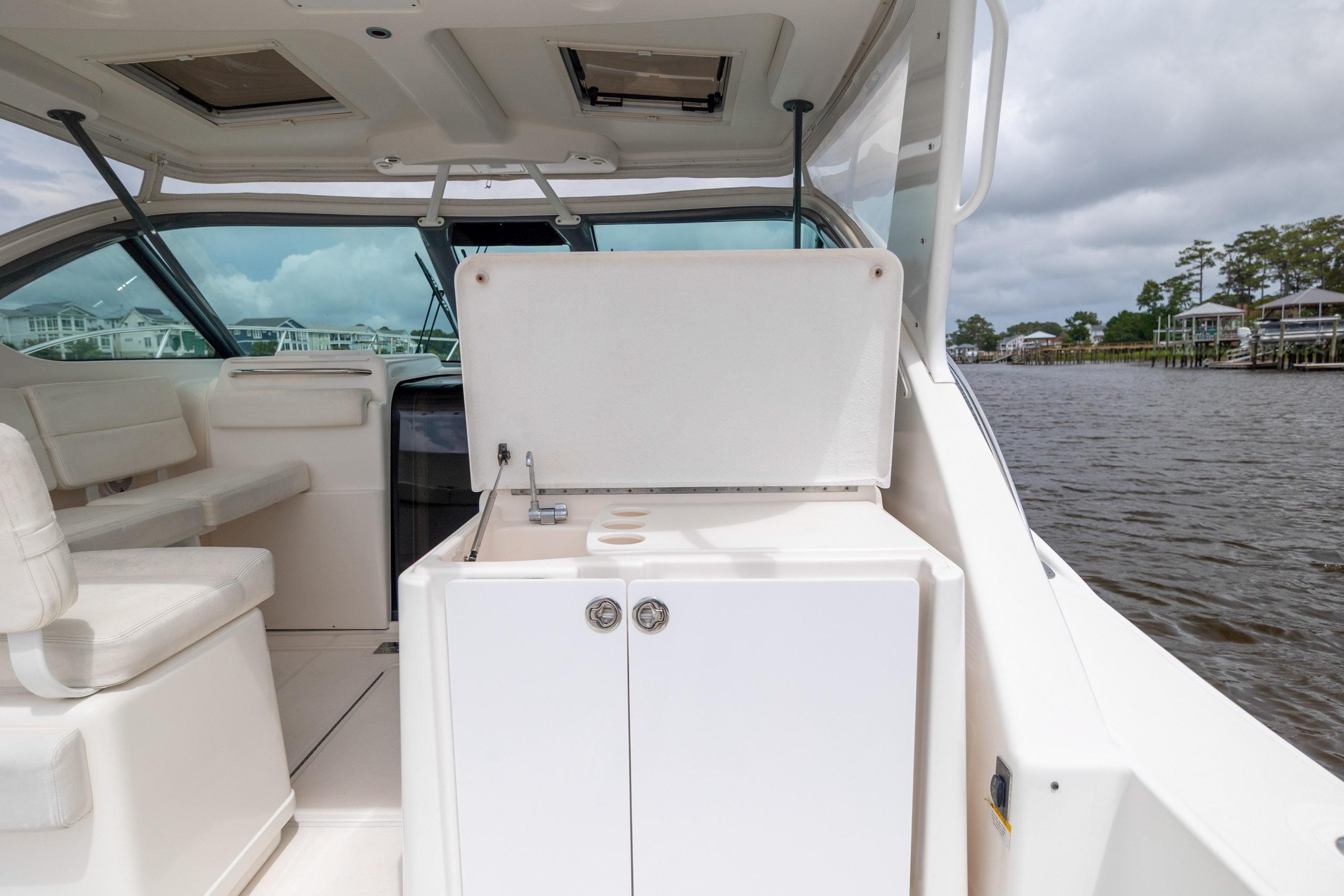2004 Tiara Yachts 3200 Open interior with seating and storage, docked by a scenic waterfront.