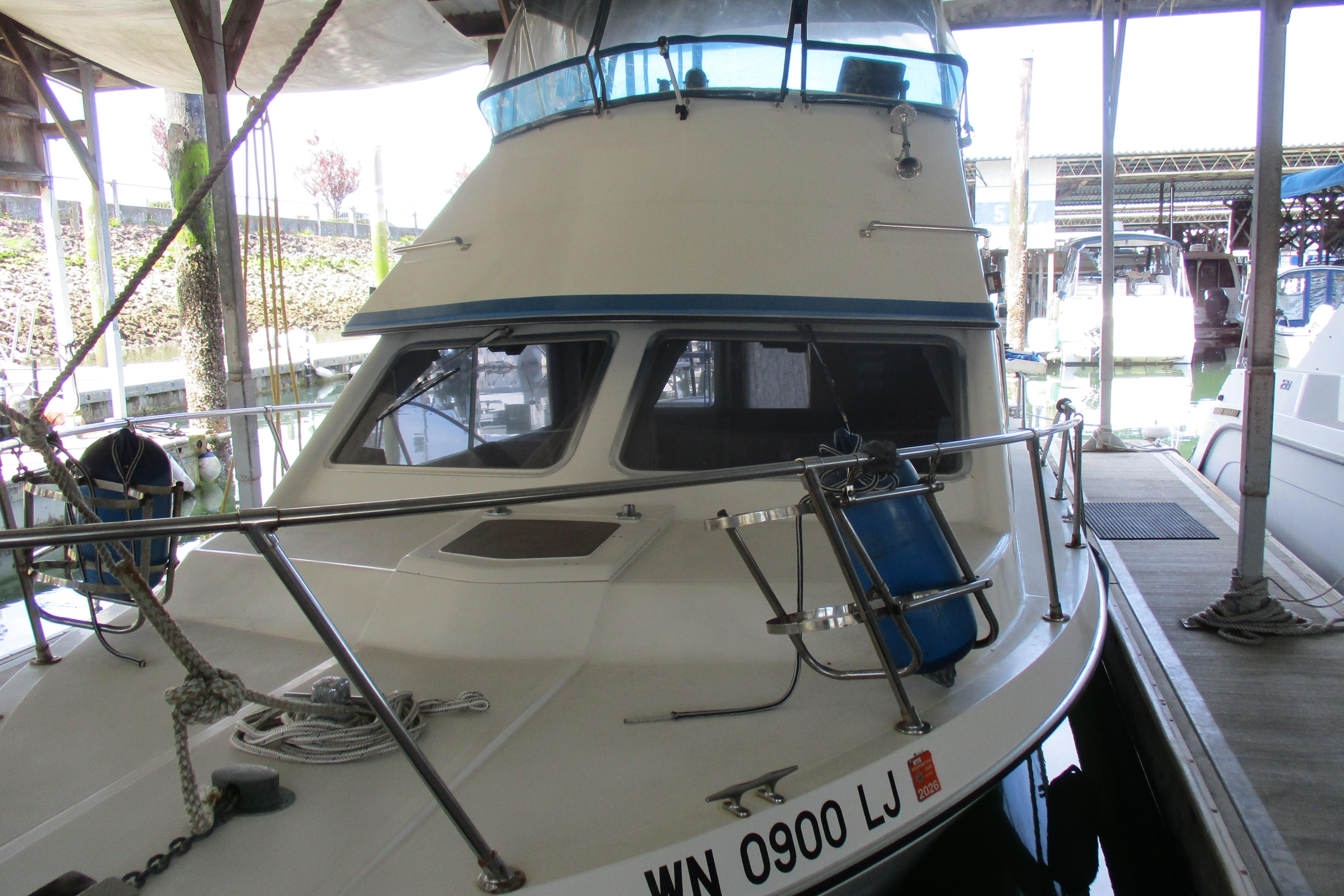 1988 Commander 26 boat docked in marina, featuring blue accents and registration number.