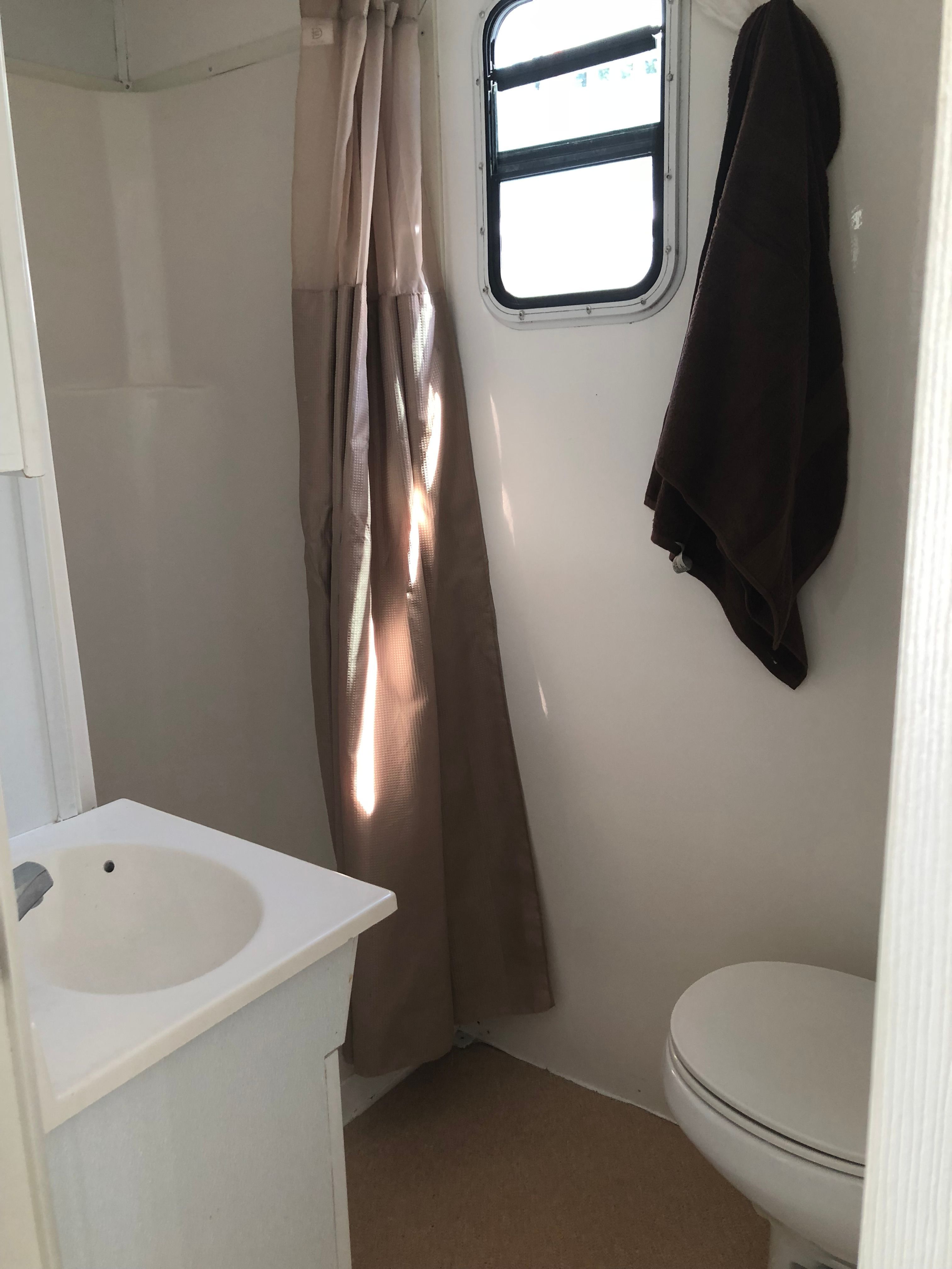 A bathroom in a 2004 42 ft Catamaran with a sink, toilet, and window.