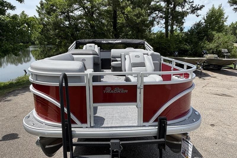 2026 Sun Tracker SportFish 20 DLX pontoon boat with red exterior, parked near a scenic lake.