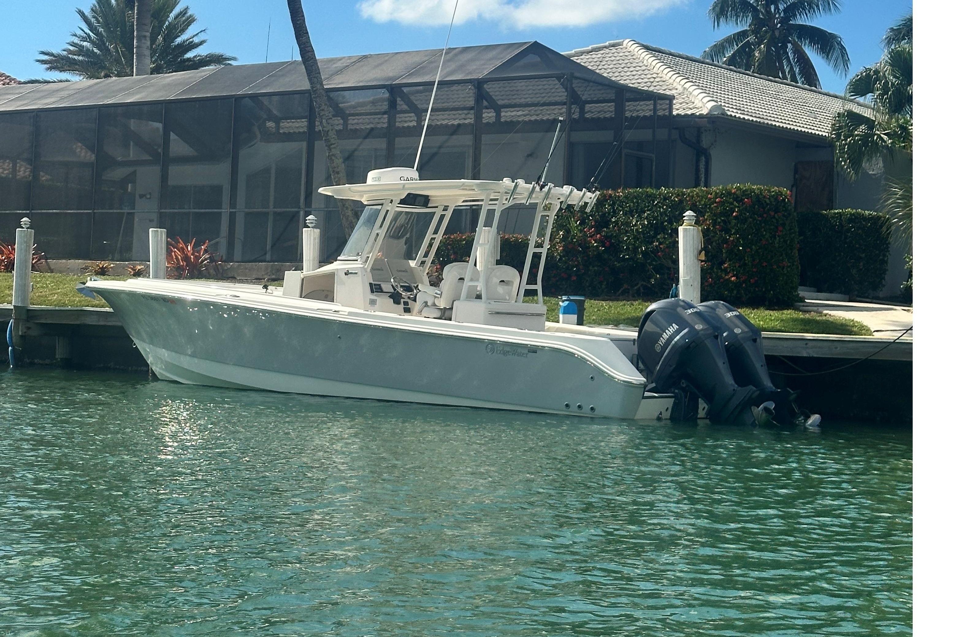2015 Edgewater 320CC boat docked by waterfront home with twin Yamaha engines.