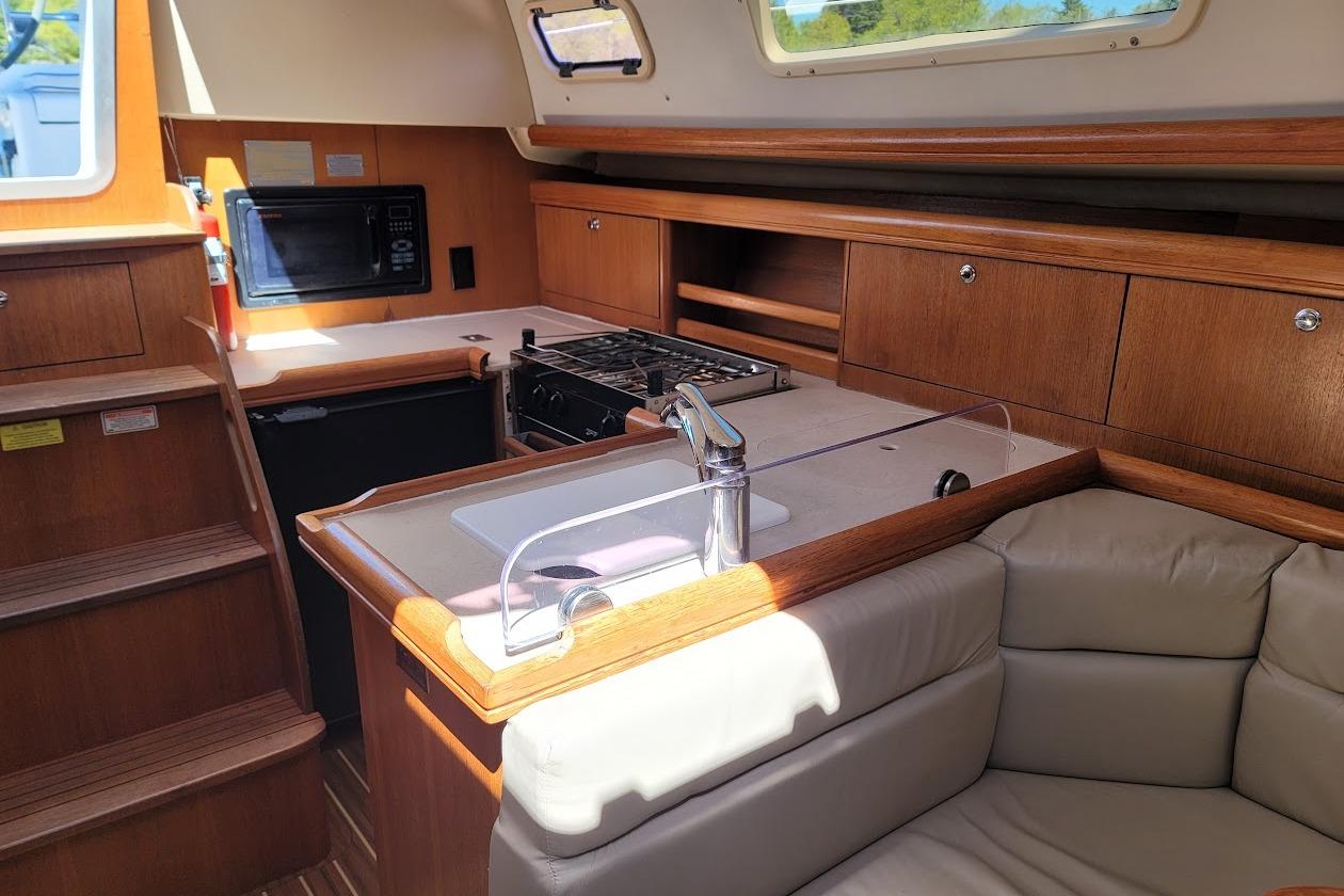 Interior of 2005 Hunter 33 sailboat galley with wood cabinetry and modern appliances.