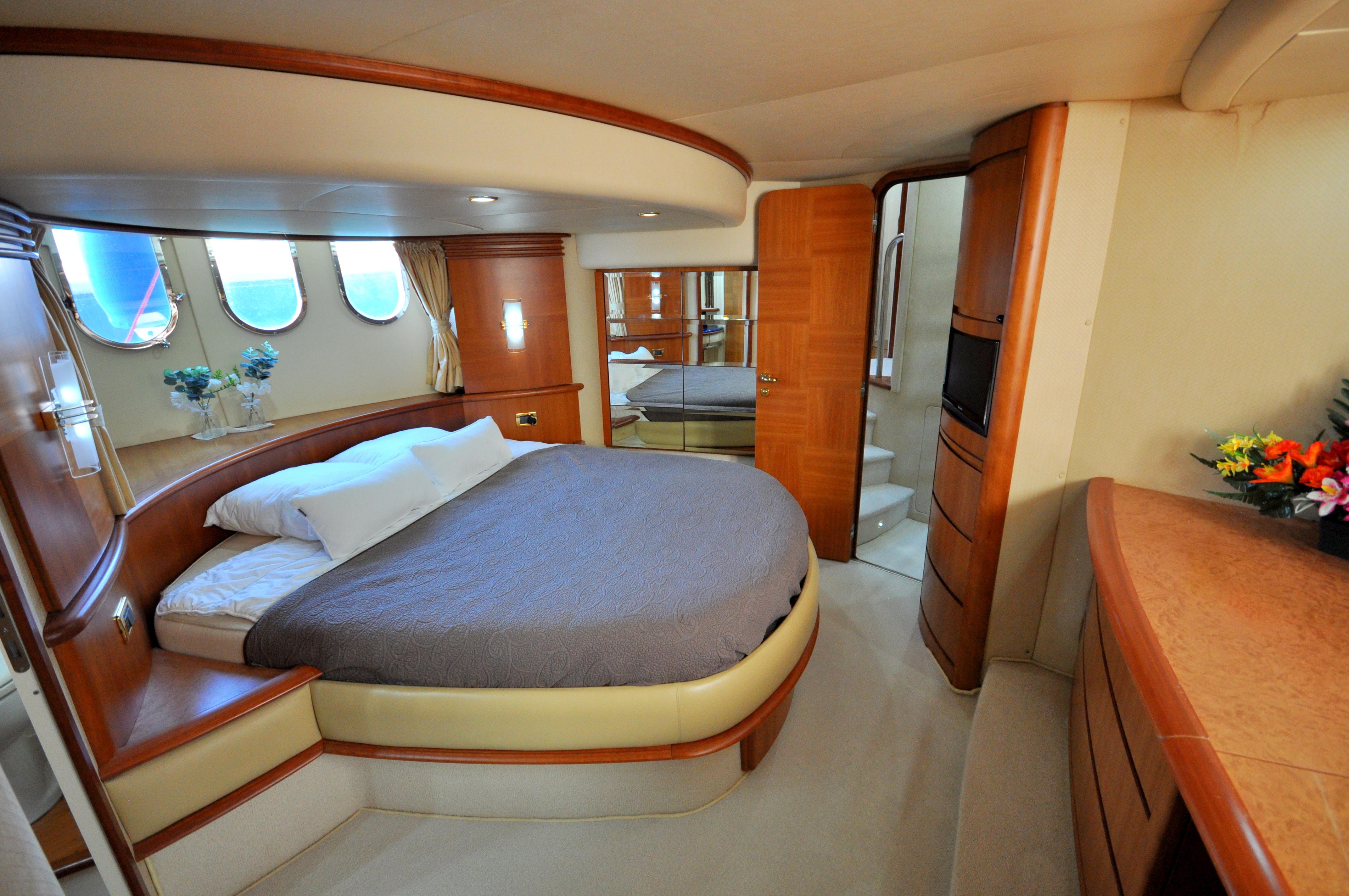 Luxurious 2005 Azimut 62 yacht bedroom with elegant wood finishes and cozy bedding.