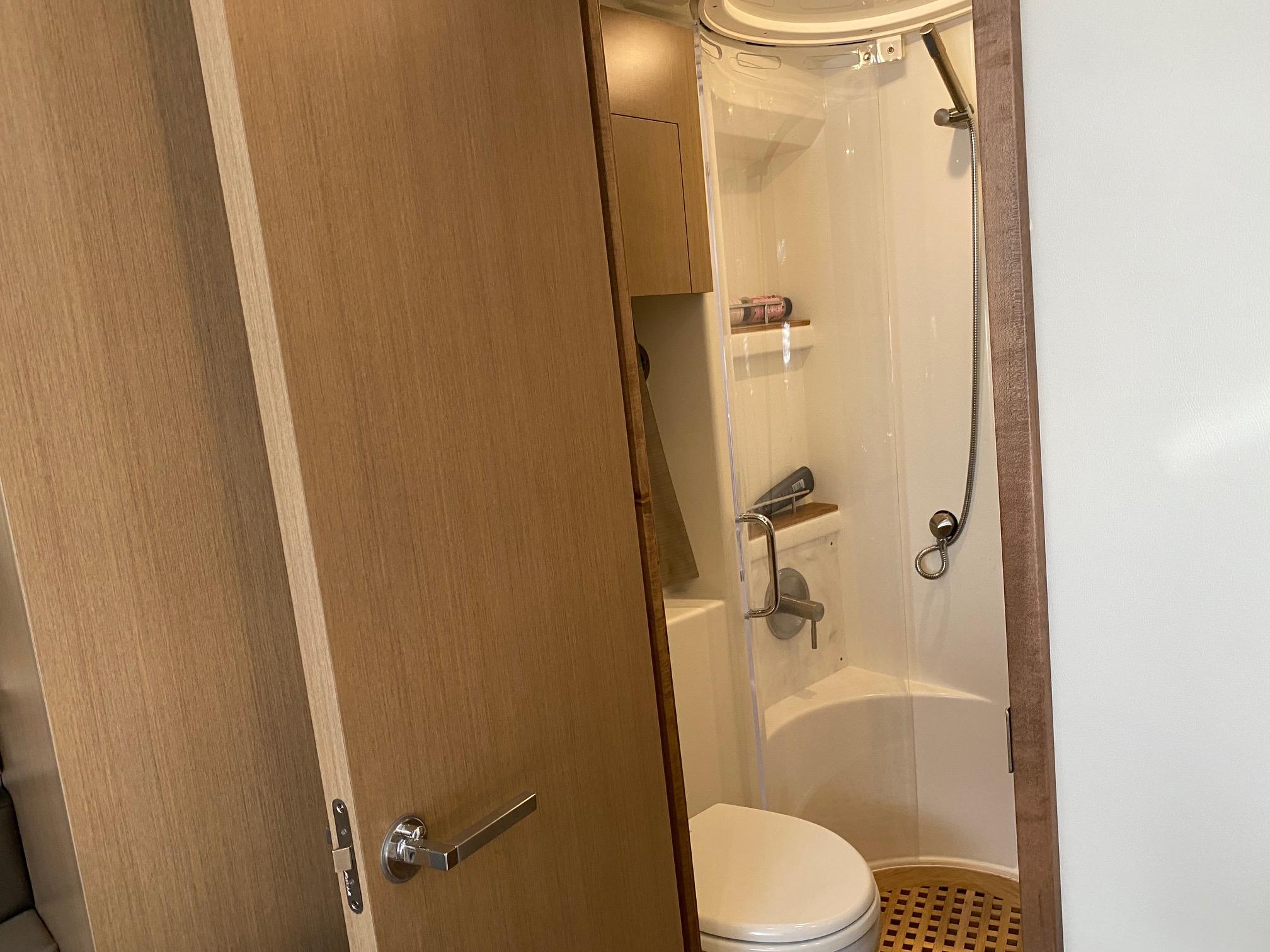 2018 Sea Ray 400 Fly yacht bathroom with shower and wooden door.