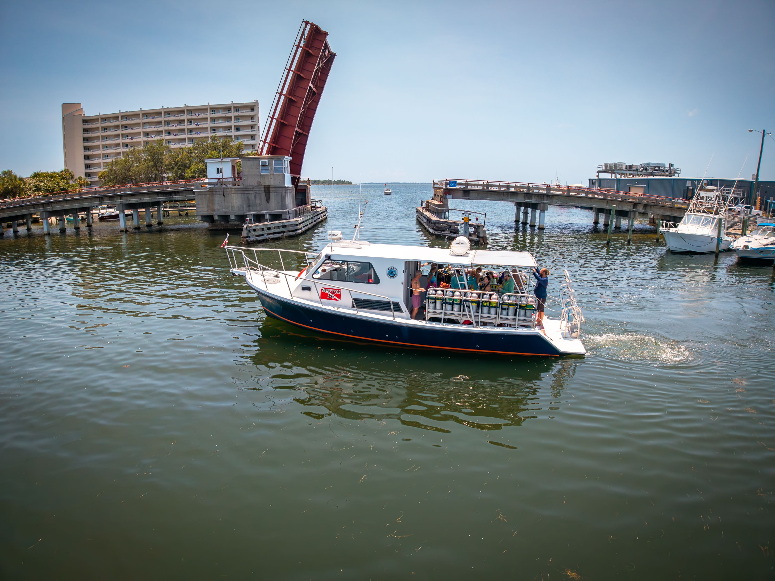 A 2019 Newton 36' Dive Special boat passes under an open bridge.
