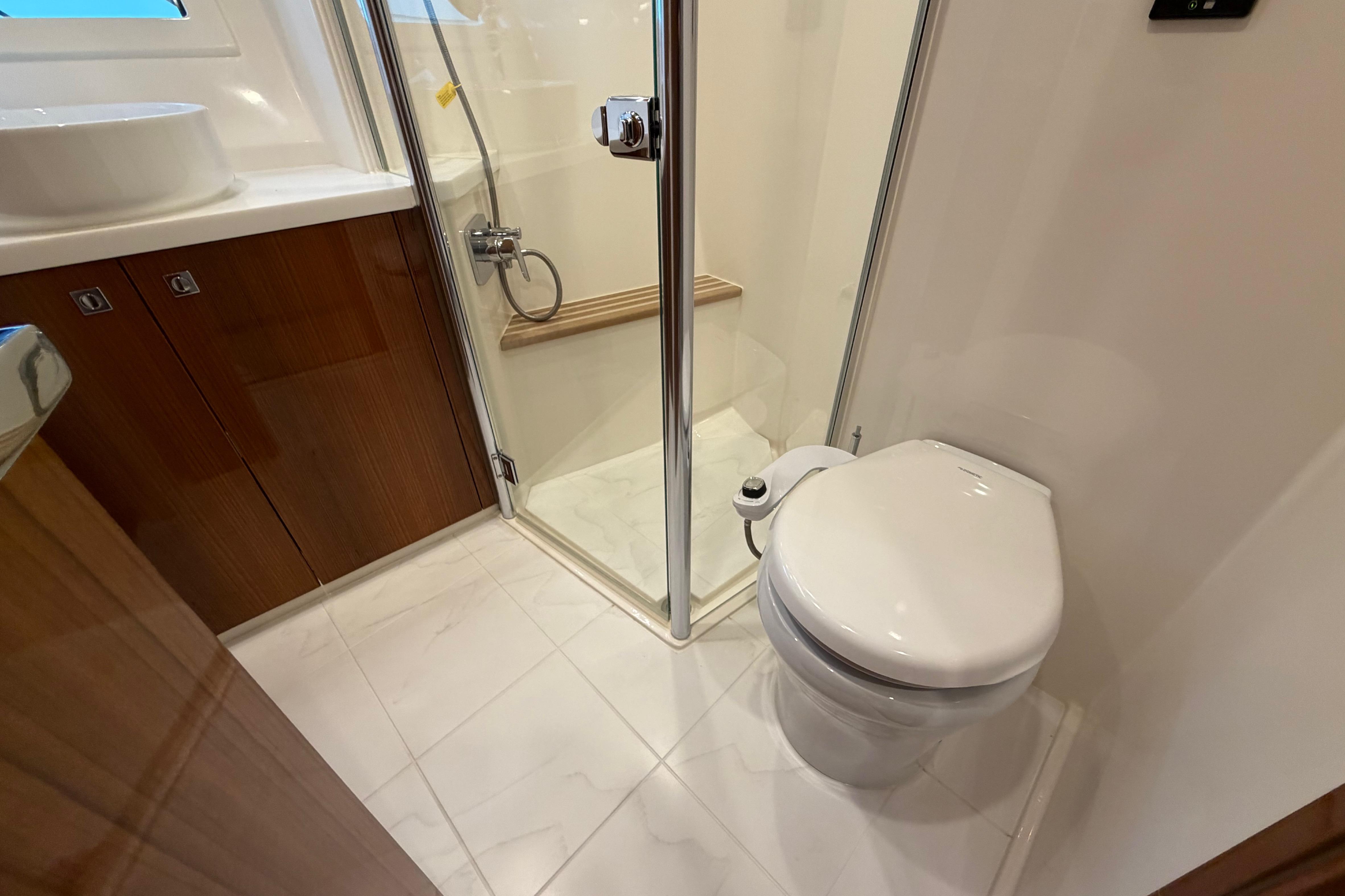Luxurious bathroom in 2023 Riviera 645 SUV yacht with shower and toilet.