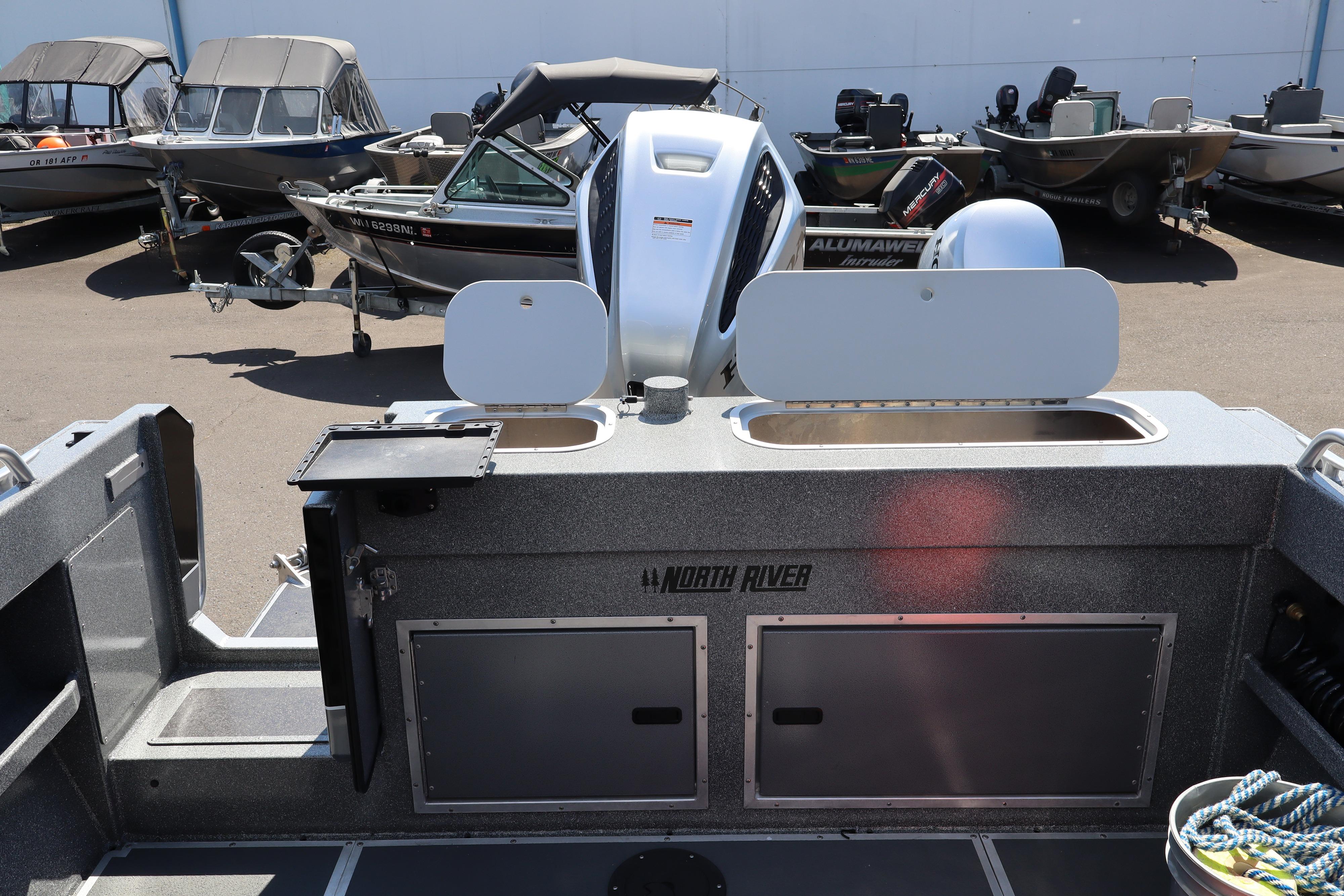 2025 NorthRiver SEAHAWK boat interior with storage compartments and motor, parked among other boats.