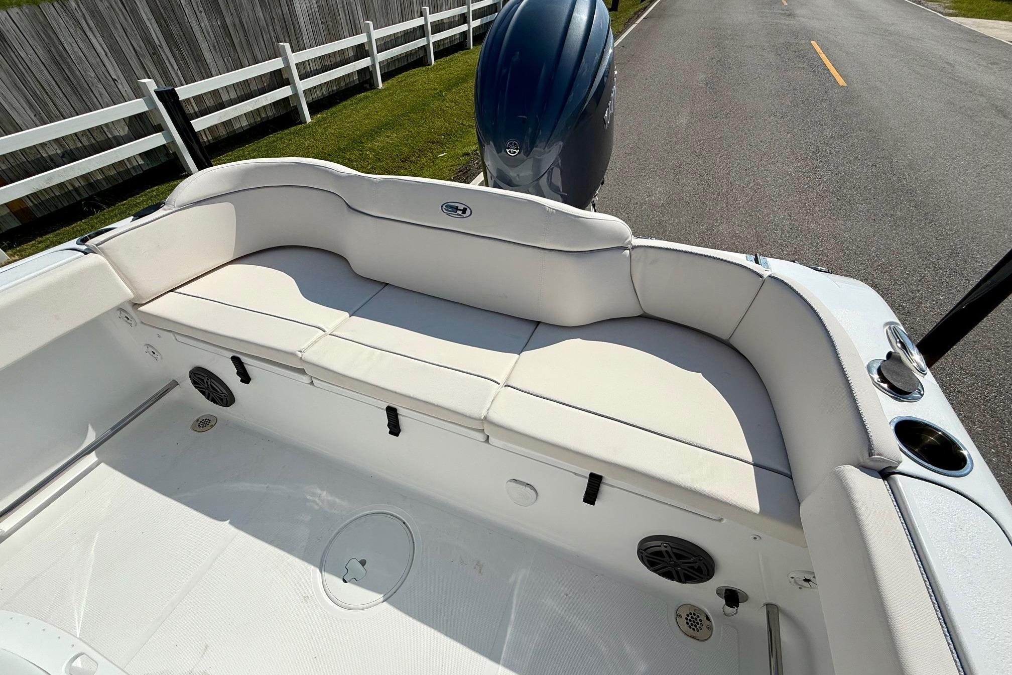 2026 Sea Hunt Ultra 229 boat interior with cushioned seating and motor, parked on a road.