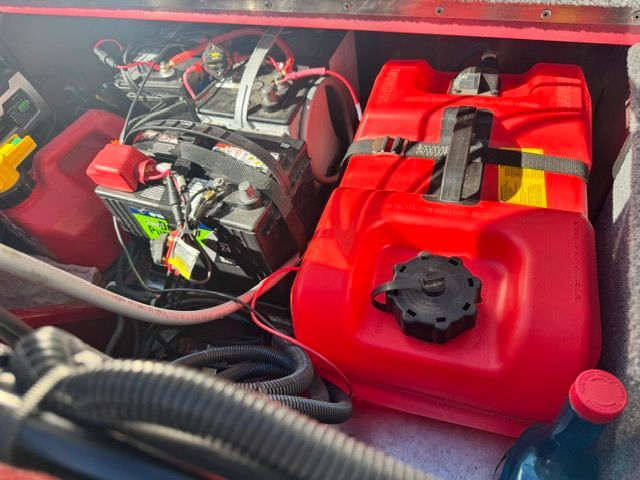 A red fuel tank and a battery are visible in the boat's storage compartment.