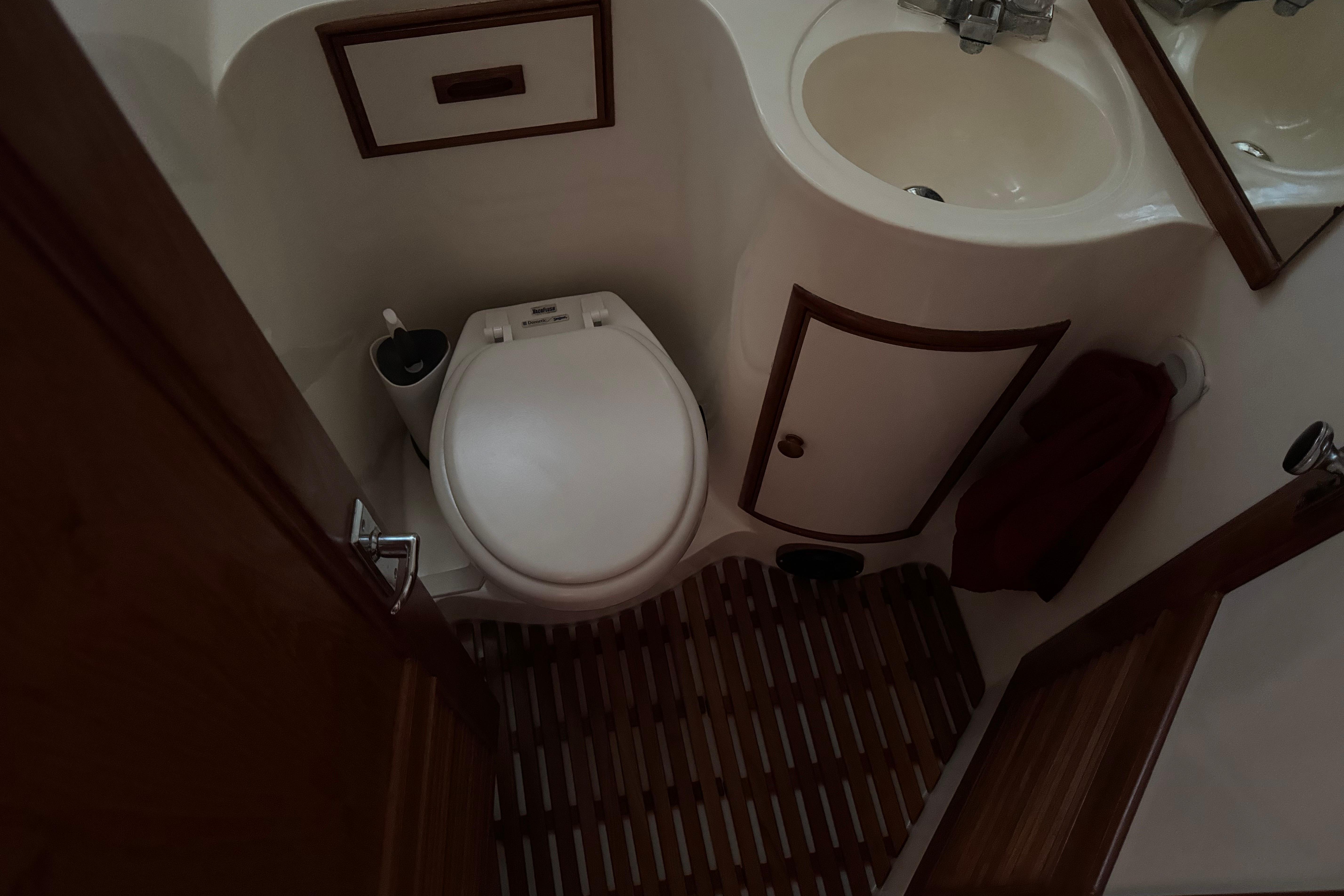 Compact bathroom in a 1987 President 37 yacht, featuring a toilet and sink.