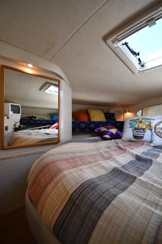 Cozy cabin interior of 1997 Sea Ray 400 Sundancer with bed, mirror, and skylight.