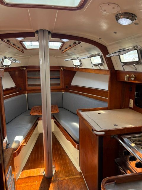 Interior of a 1983 C&C Landfall with wood finish and gray cushions.