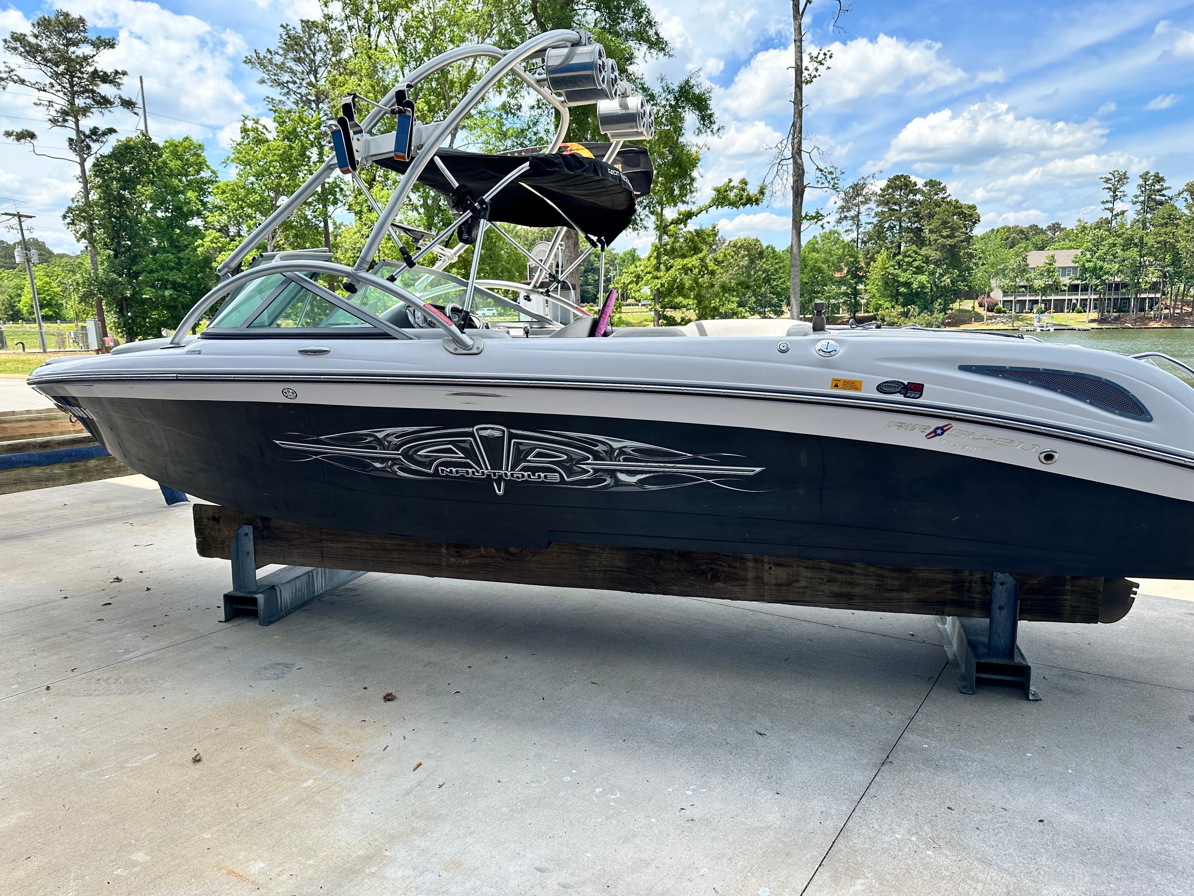 A 2007 Nautique SV 211 boat is on a dock with trees in the background.