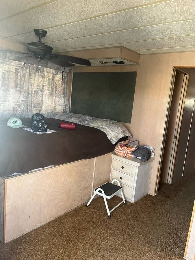 Interior of a 1993 Lakeview houseboat with bed and fan.